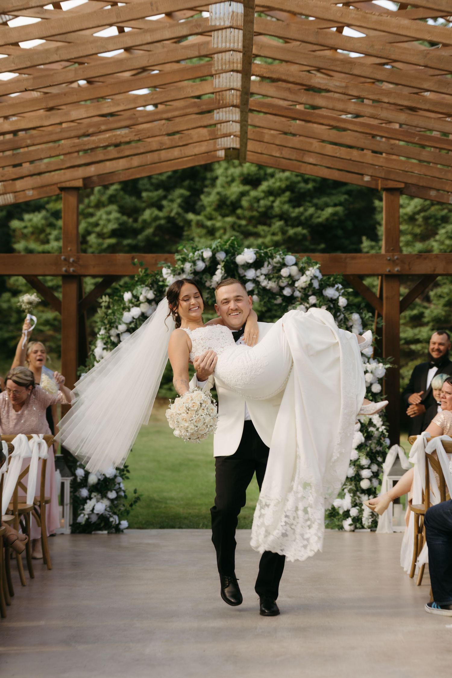 A sequence of wedding photos showing a couple dipping and dancing under a wooden pergola decorated with white floral arrangements.