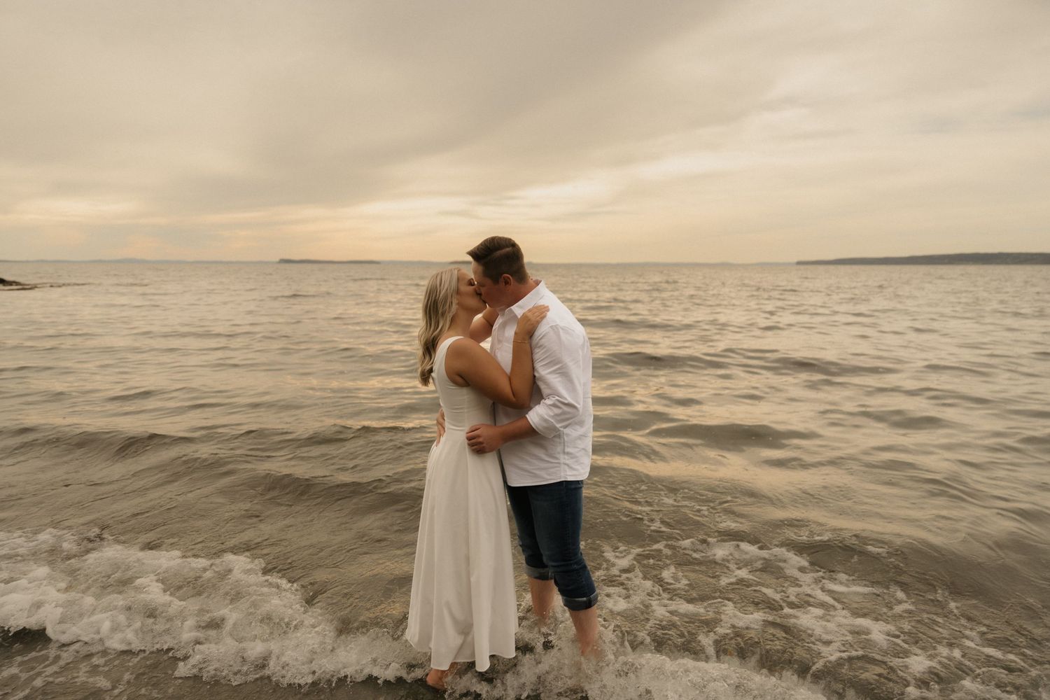Intimate beach moment captured during sunset with waves crashing on rocky shoreline.