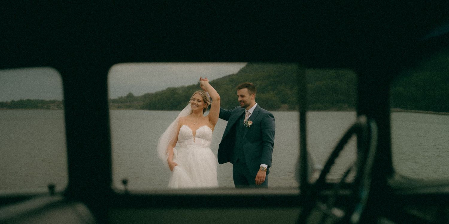 A couple walks along a scenic lakeside path during their wedding photoshoot in nature.