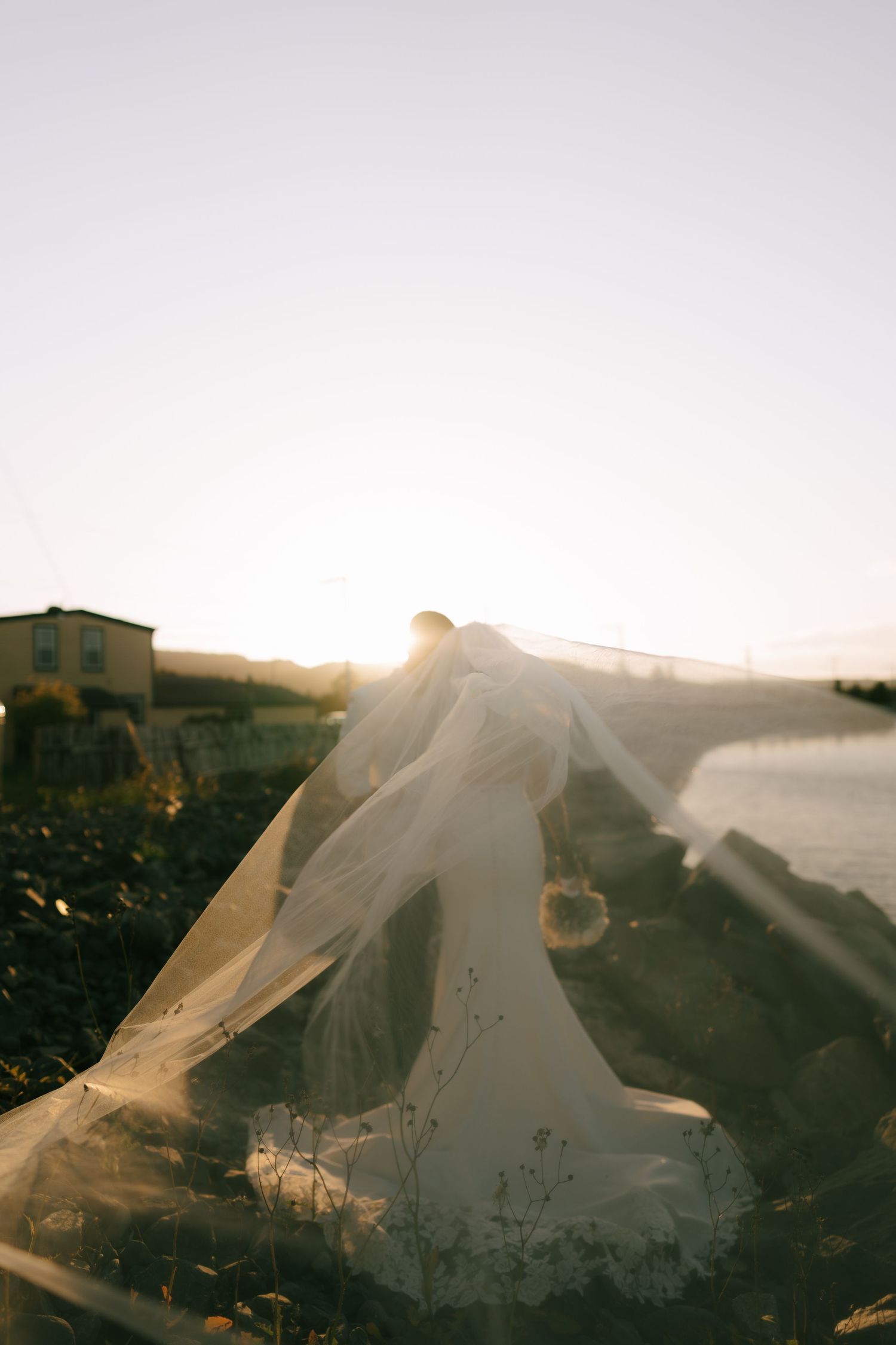 Plastic sheets or tarps billowing in the wind at sunset create an ethereal silhouette against a glowing sky.