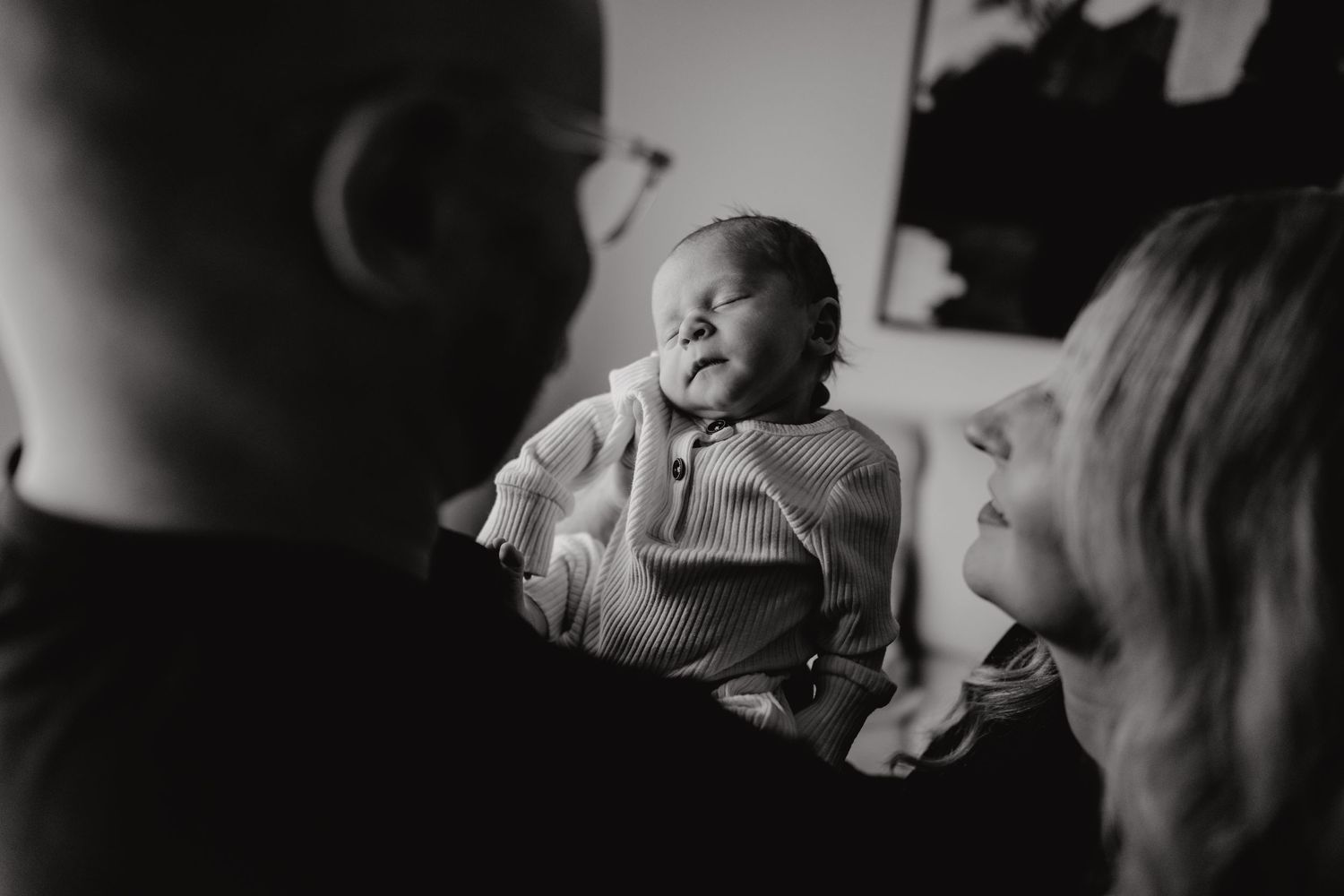 Black and white moment of tender family bonding at home with a newborn.