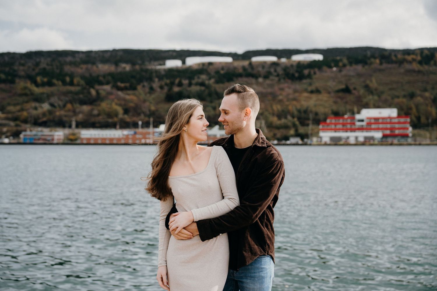A romantic waterfront portrait with a scenic harbor and mountain landscape in the background.