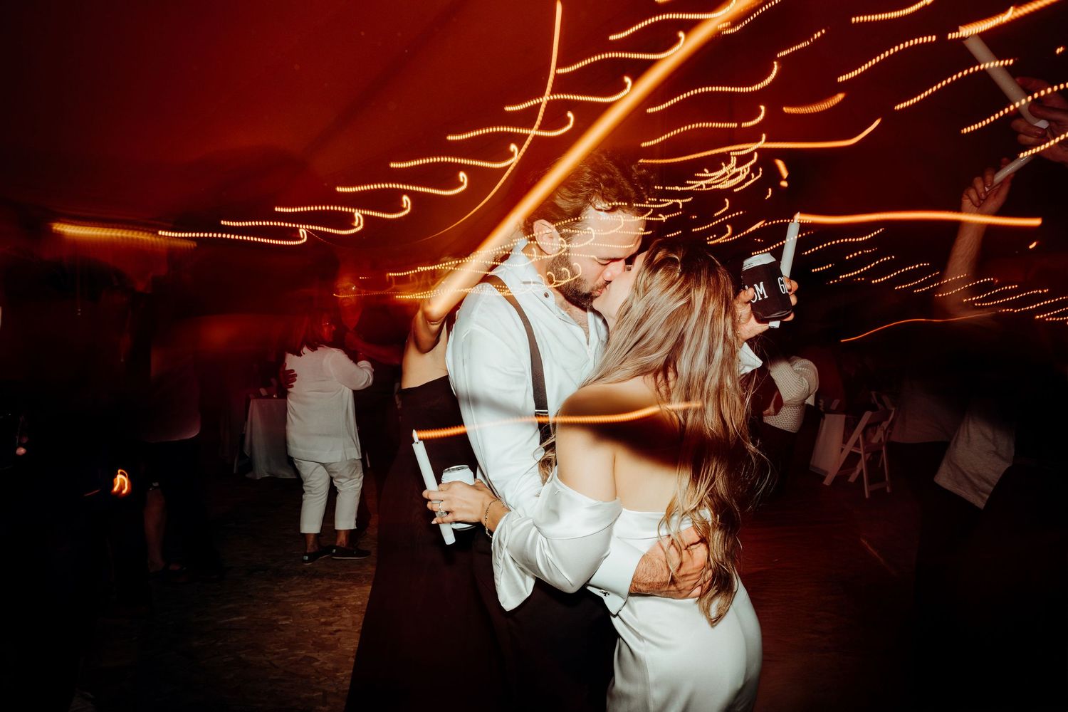 Dancing couple create light trails at night with sparklers during a wedding reception celebration.