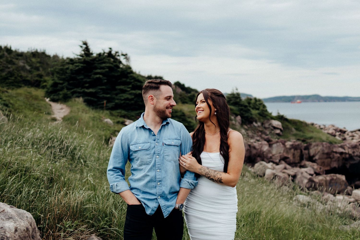 Two people share loving moments during a coastal photoshoot with ocean views.