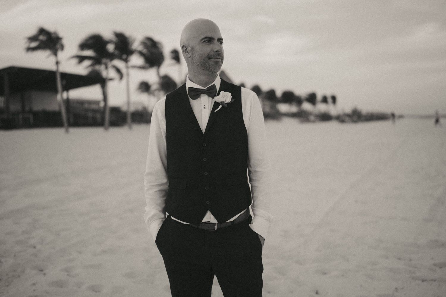Black and white portrait of newlyweds on a beach with palm trees.