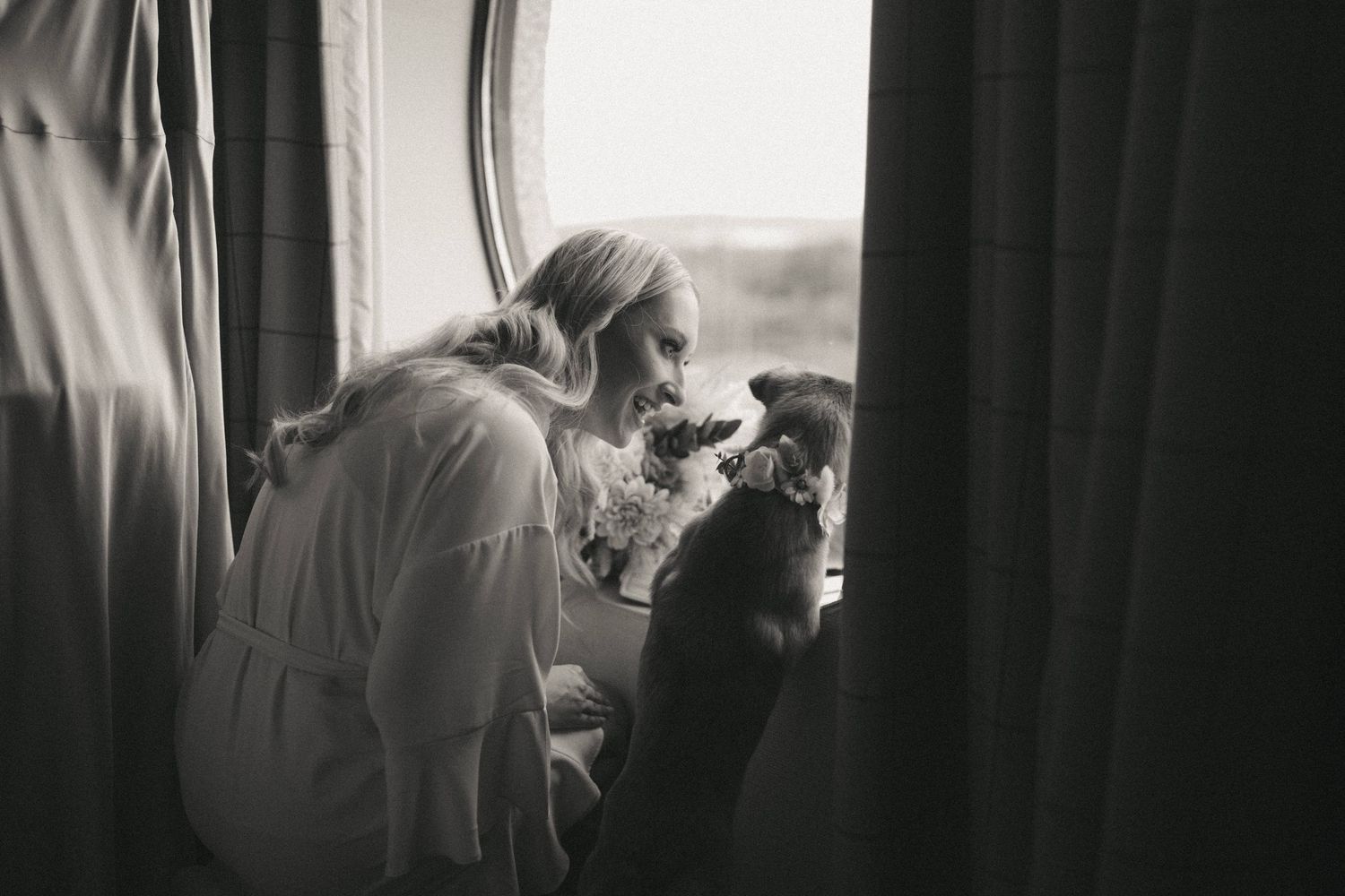 Bride getting ready in white robe against dark background during wedding preparations.