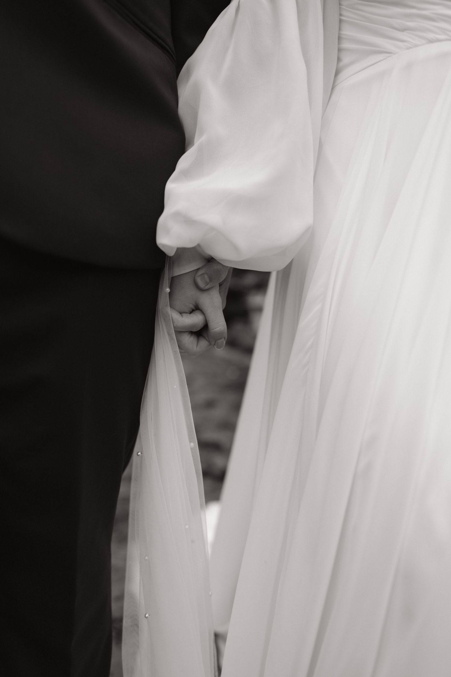 Close-up details of a flowing white wedding dress fabric creating elegant draping and folds in black and white.