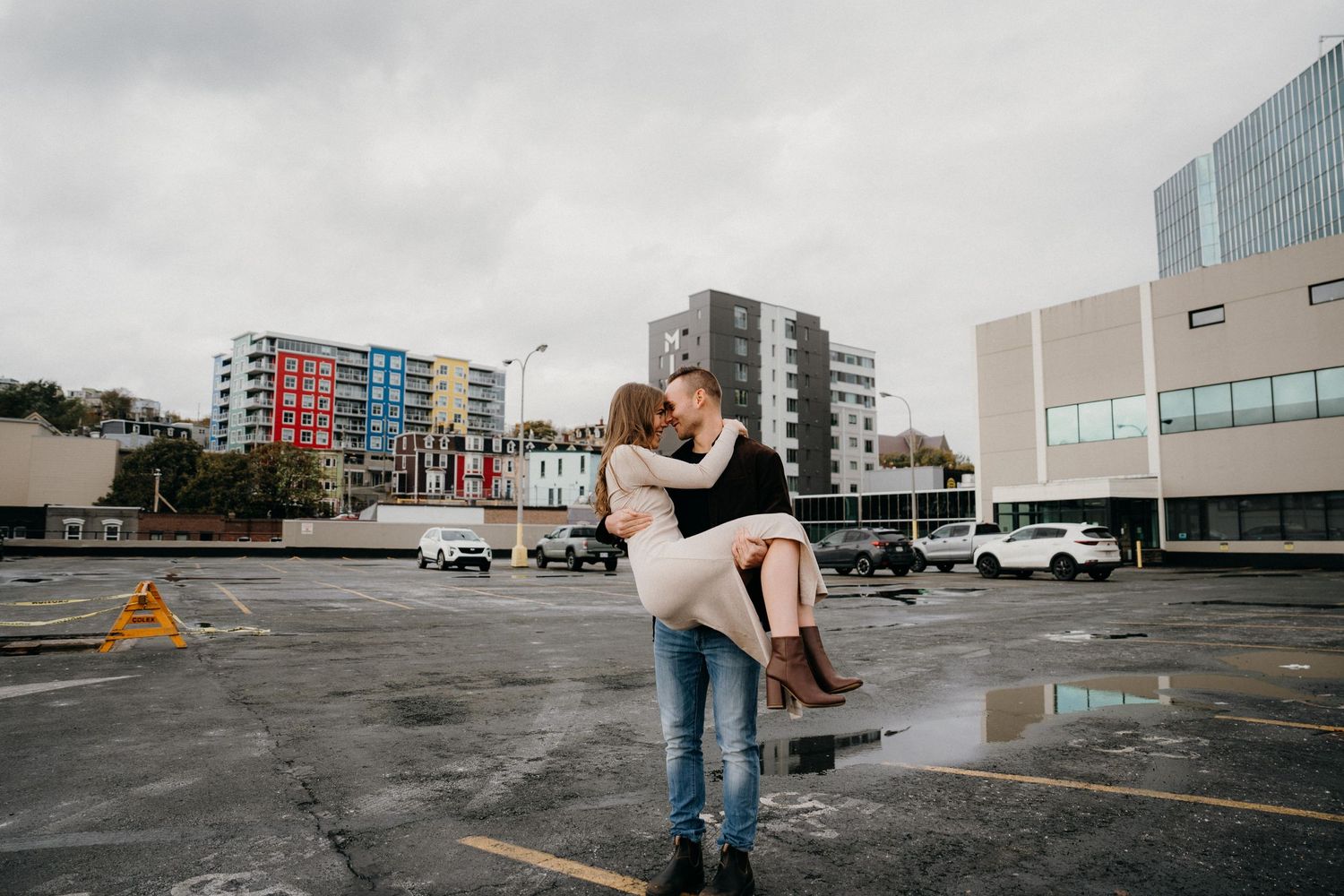 Romantic dance lift performed in a gritty urban setting with modern architecture in the background.