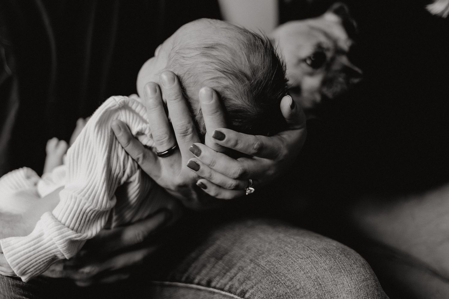 Artistic monochrome photograph focusing on gentle interaction with a newborn.