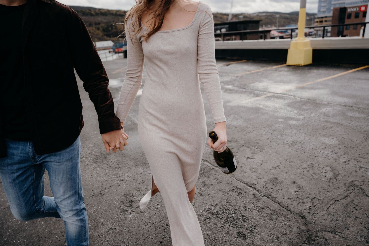 Couple holding hands while walking on concrete surface, close-up shot.
