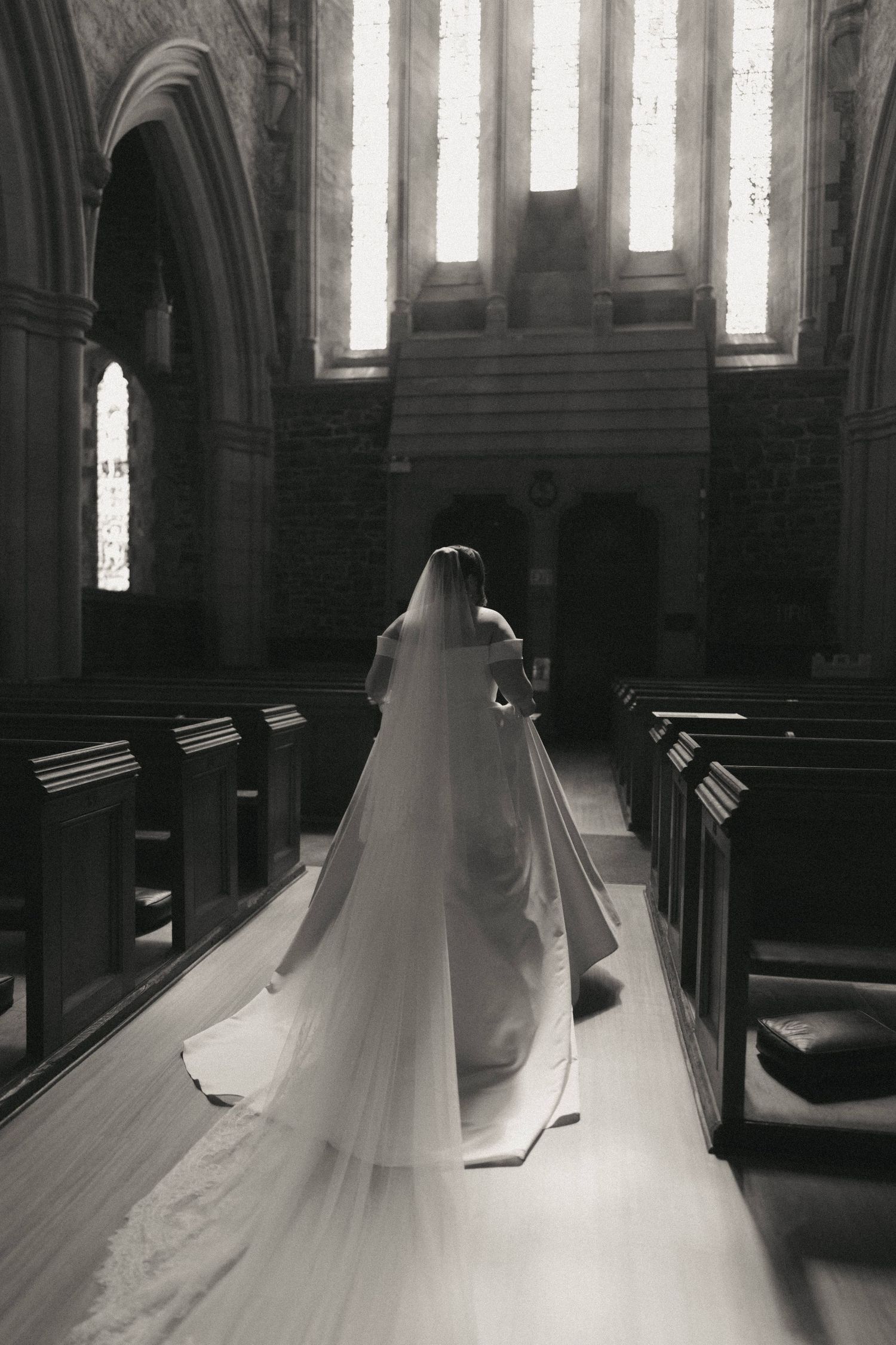Dramatic black and white photograph showing a wedding dress silhouette in a church.