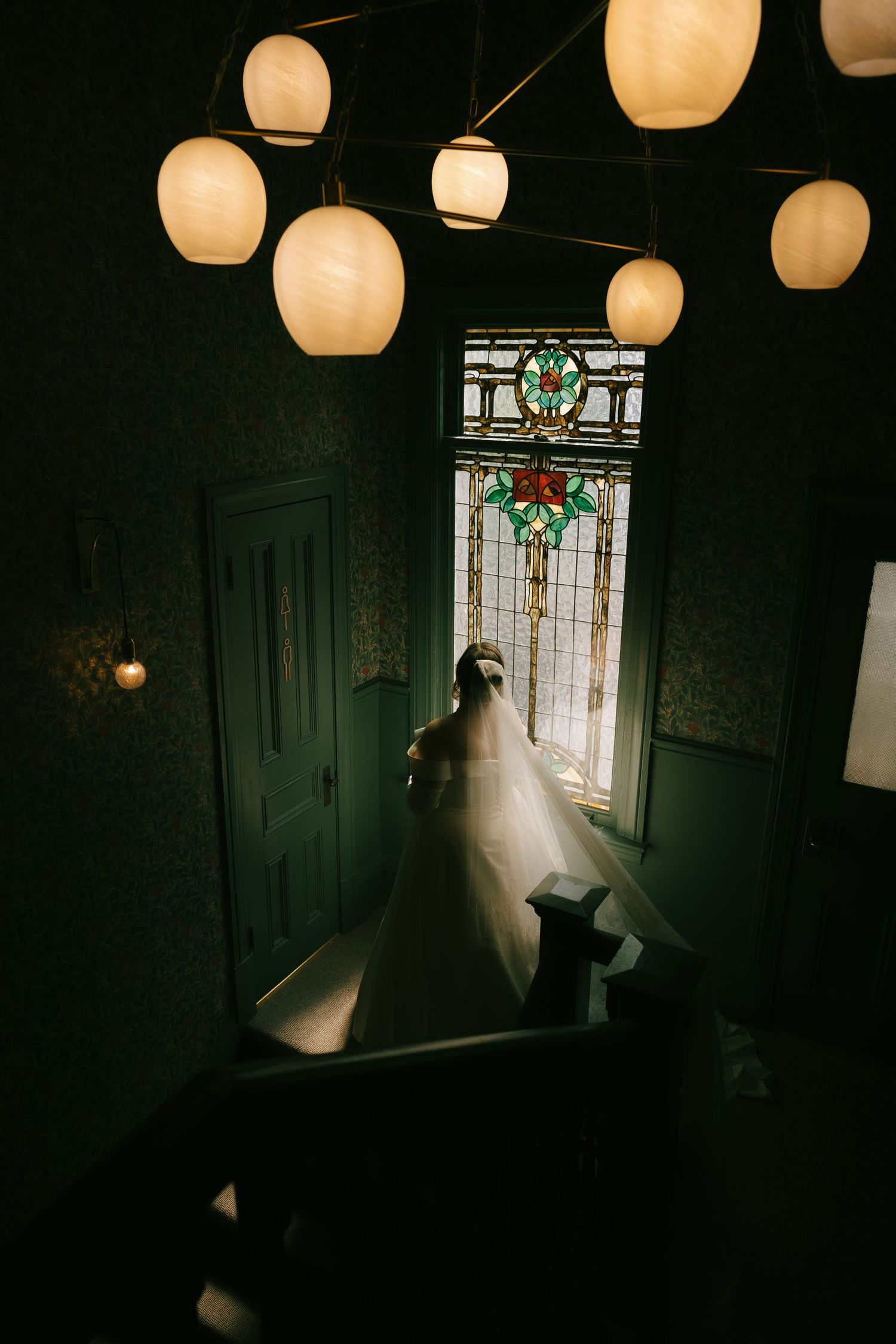 White paper lanterns illuminate a dark hallway where a wedding dress flows gracefully.