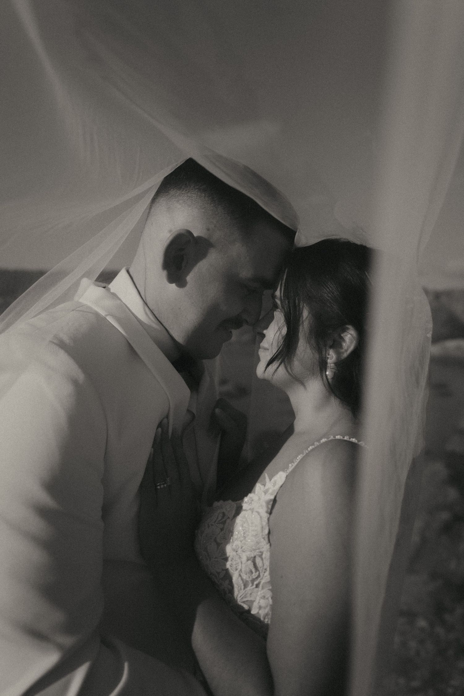 A romantic black and white photo sequence of a couple in wedding attire sharing intimate moments behind a veil.