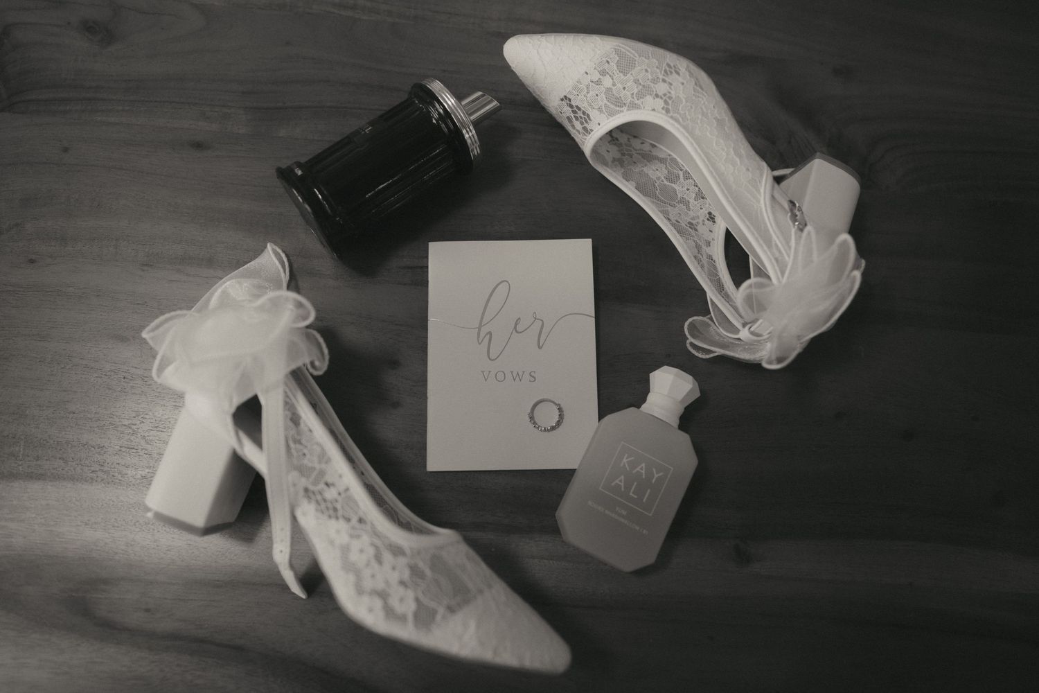 A black and white photograph shows scattered shoes and papers on a wooden floor.