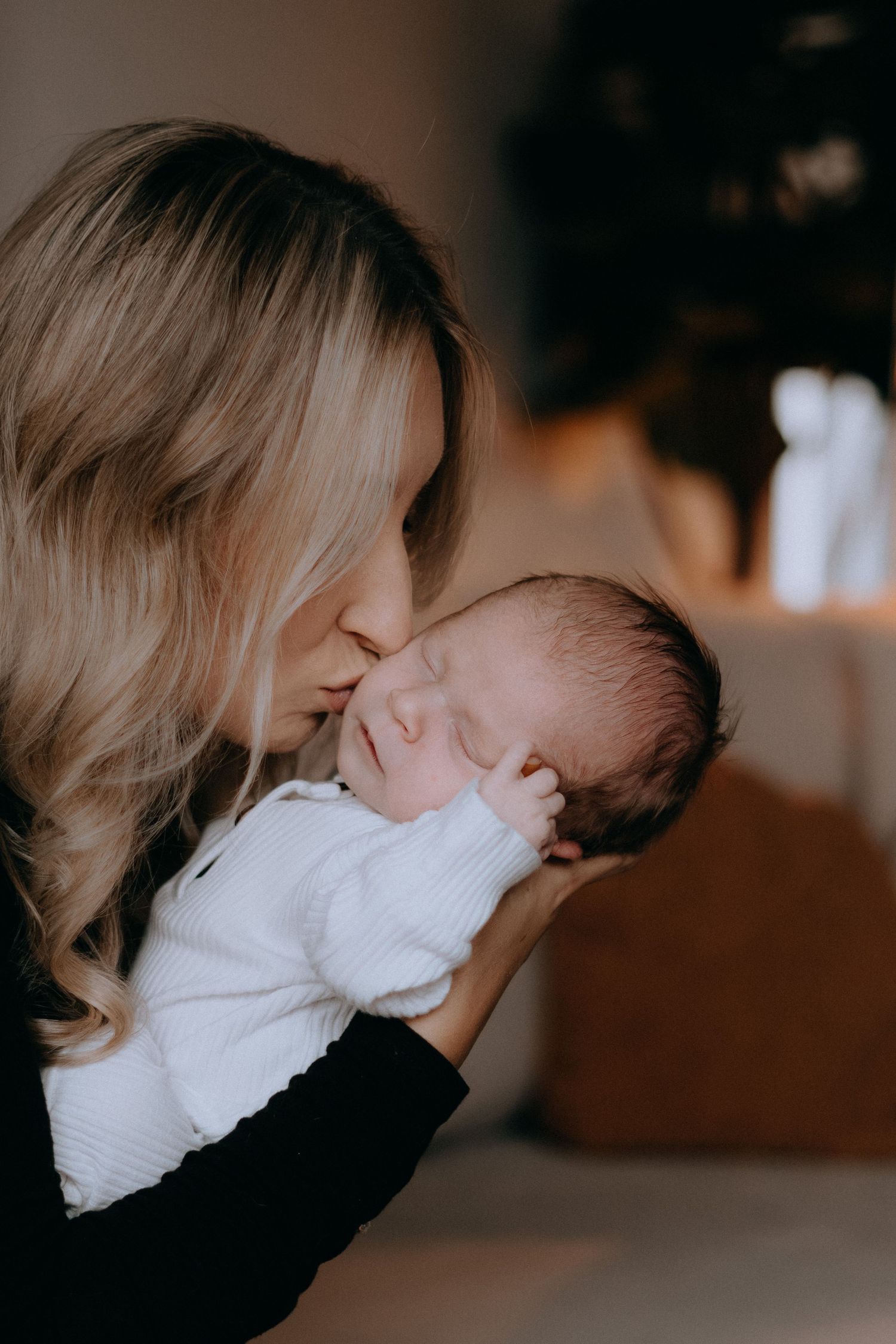 Atmospheric lifestyle session captures loving family moments in moody indoor lighting.
