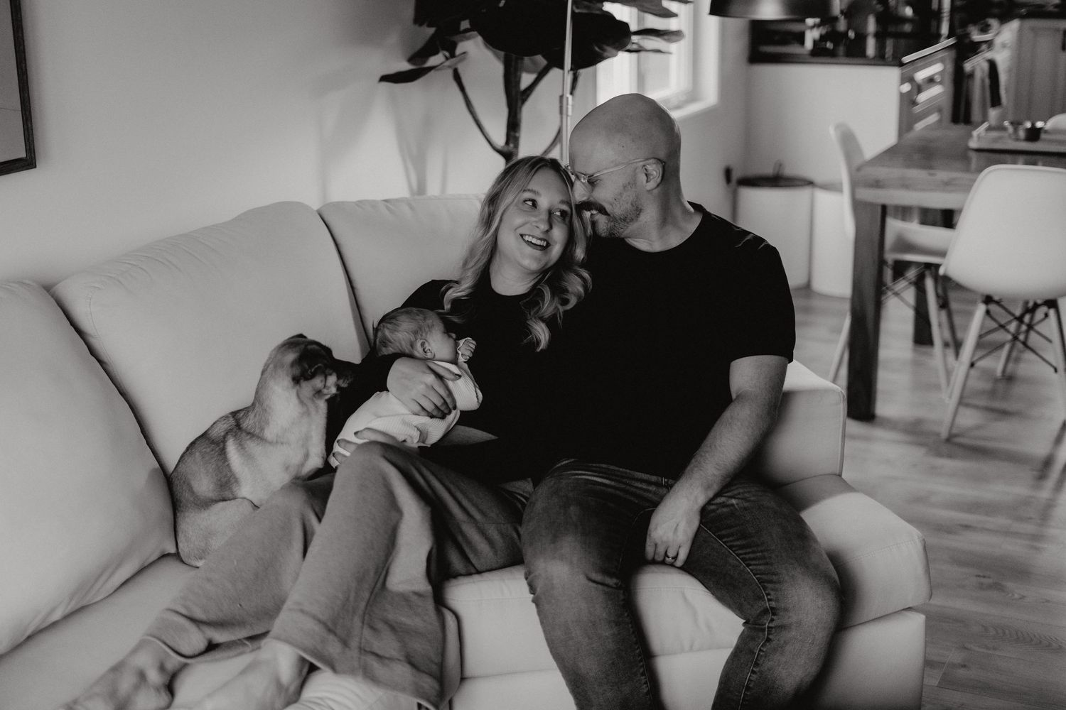 Black and white portrait of a couple sharing a tender moment on a sofa.