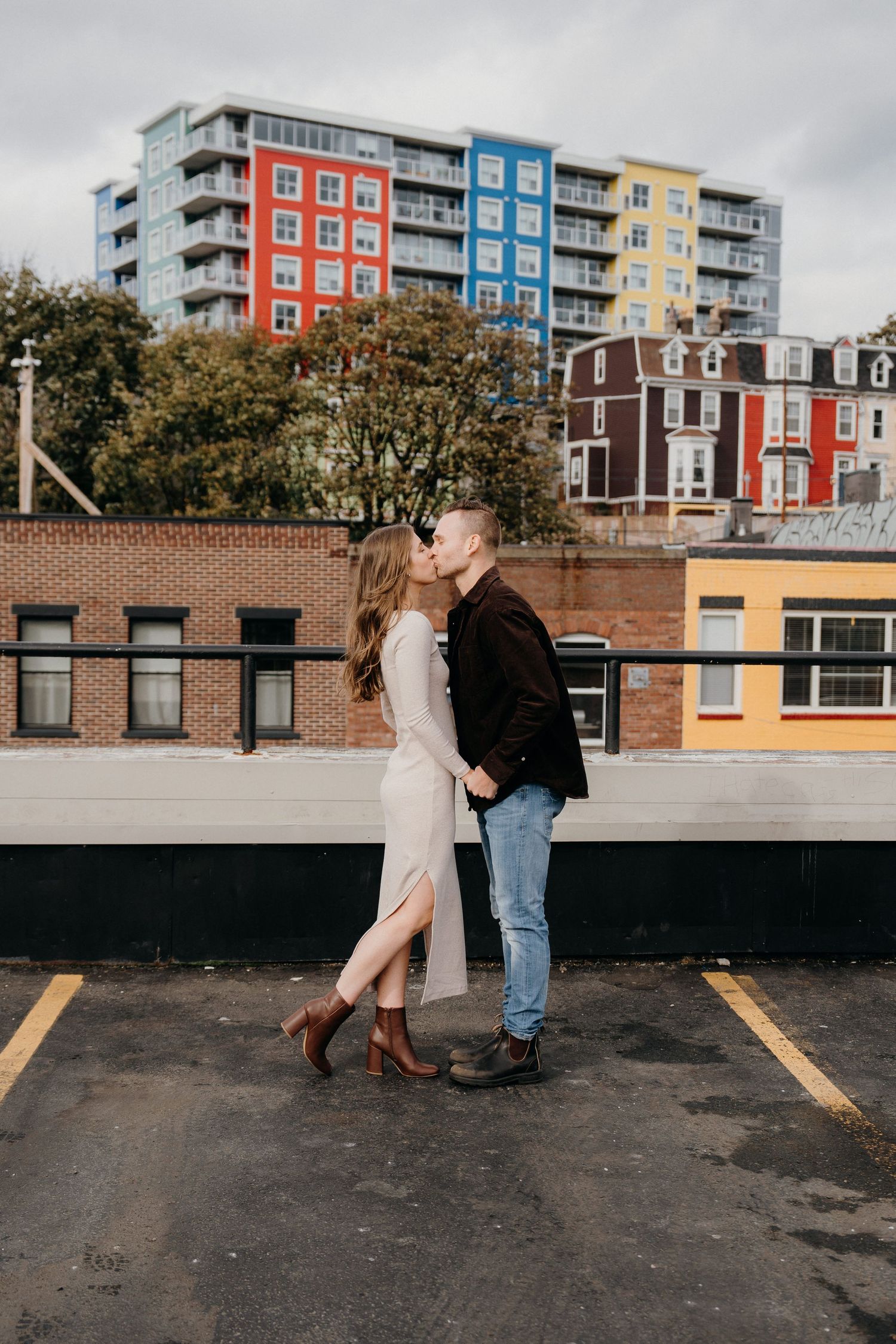 Romantic candid sequence showing couple dancing together on urban rooftop with colorful buildings behind.