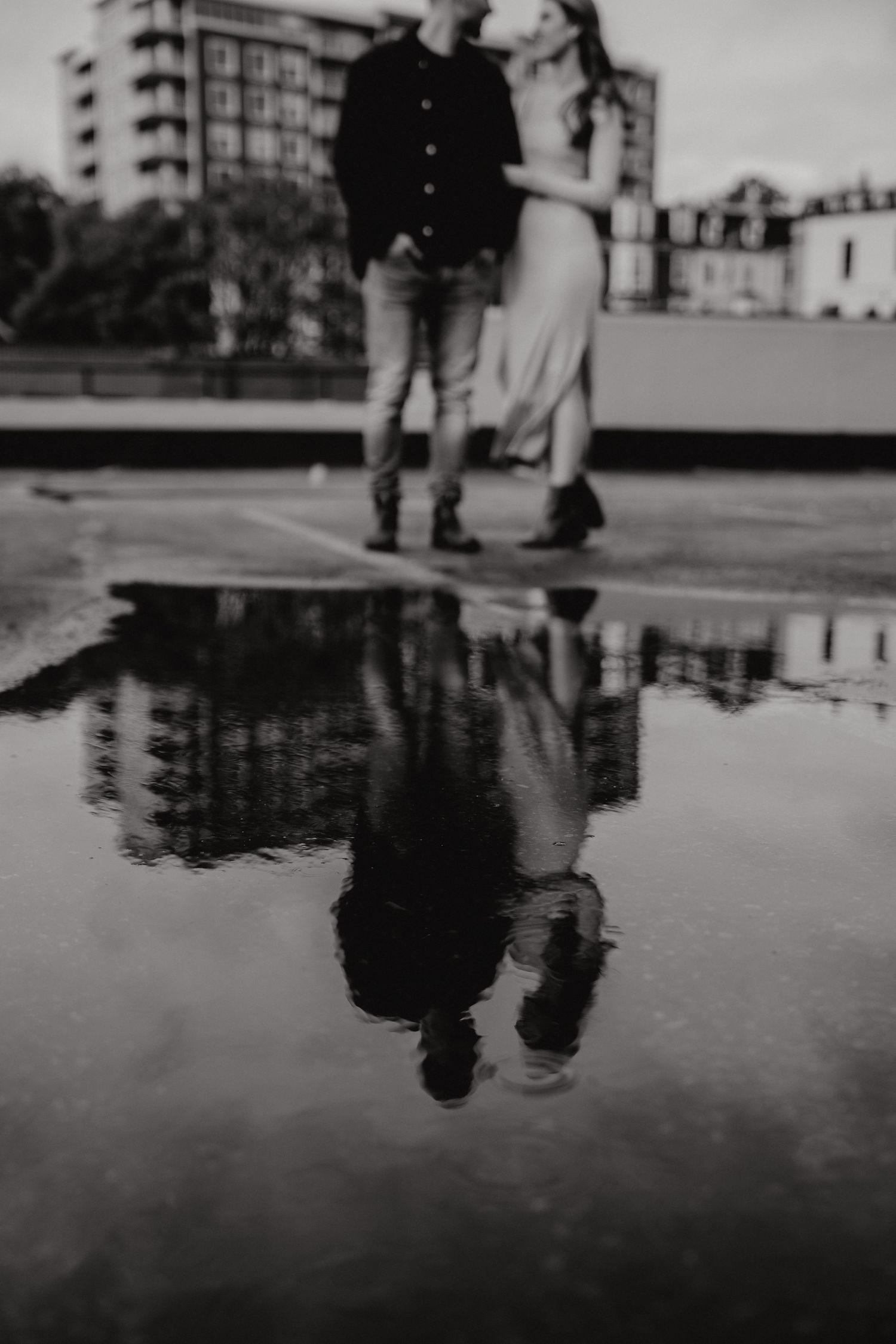 Artistic black and white shot of silhouettes reflected in a rooftop puddle.