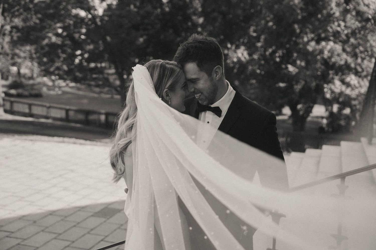 Flowing wedding dress train creates artistic movement in black and white photography.