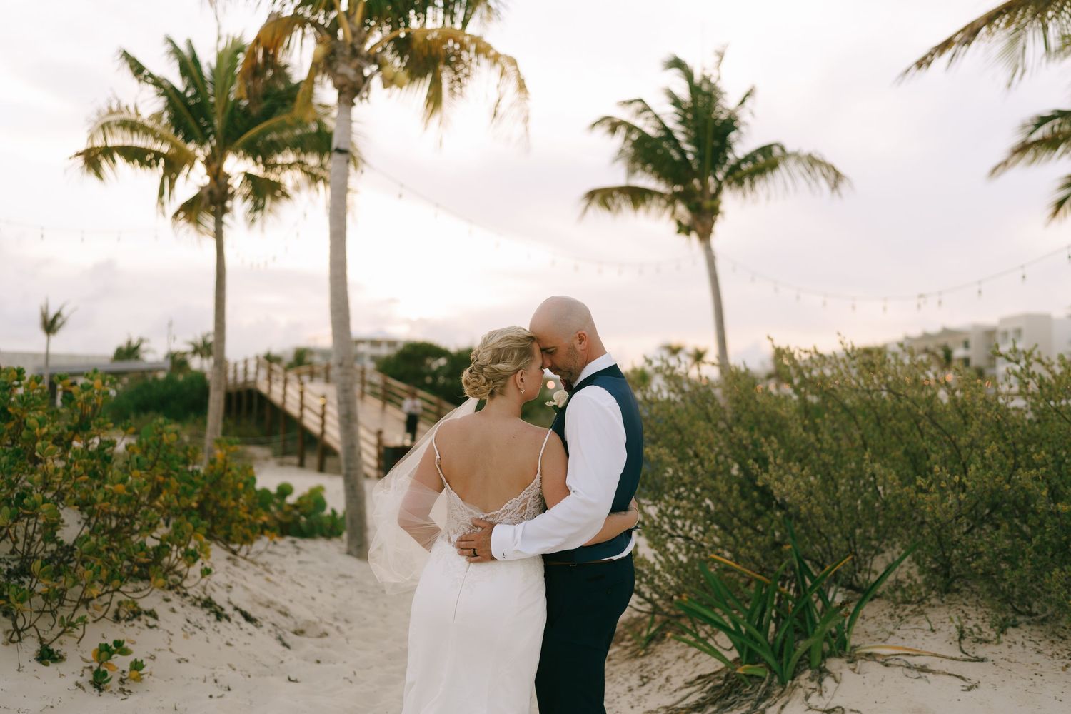 A romantic beach wedding ceremony with palm trees swaying in the breeze at sunset.
