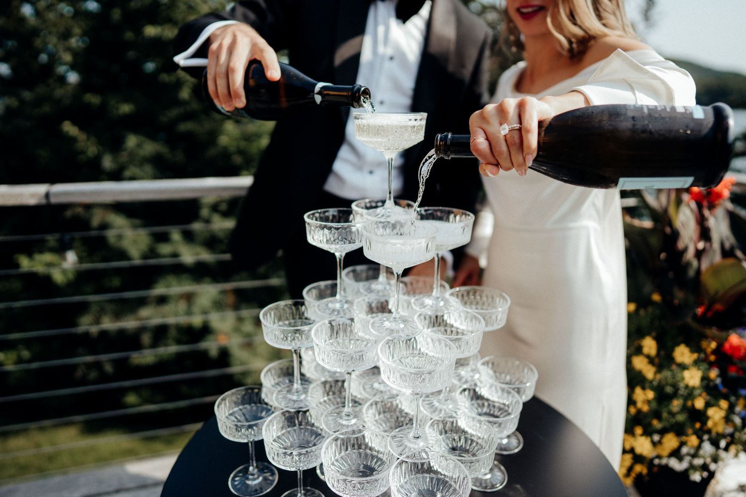 Close-up of champagne tower being poured at elegant wedding reception.