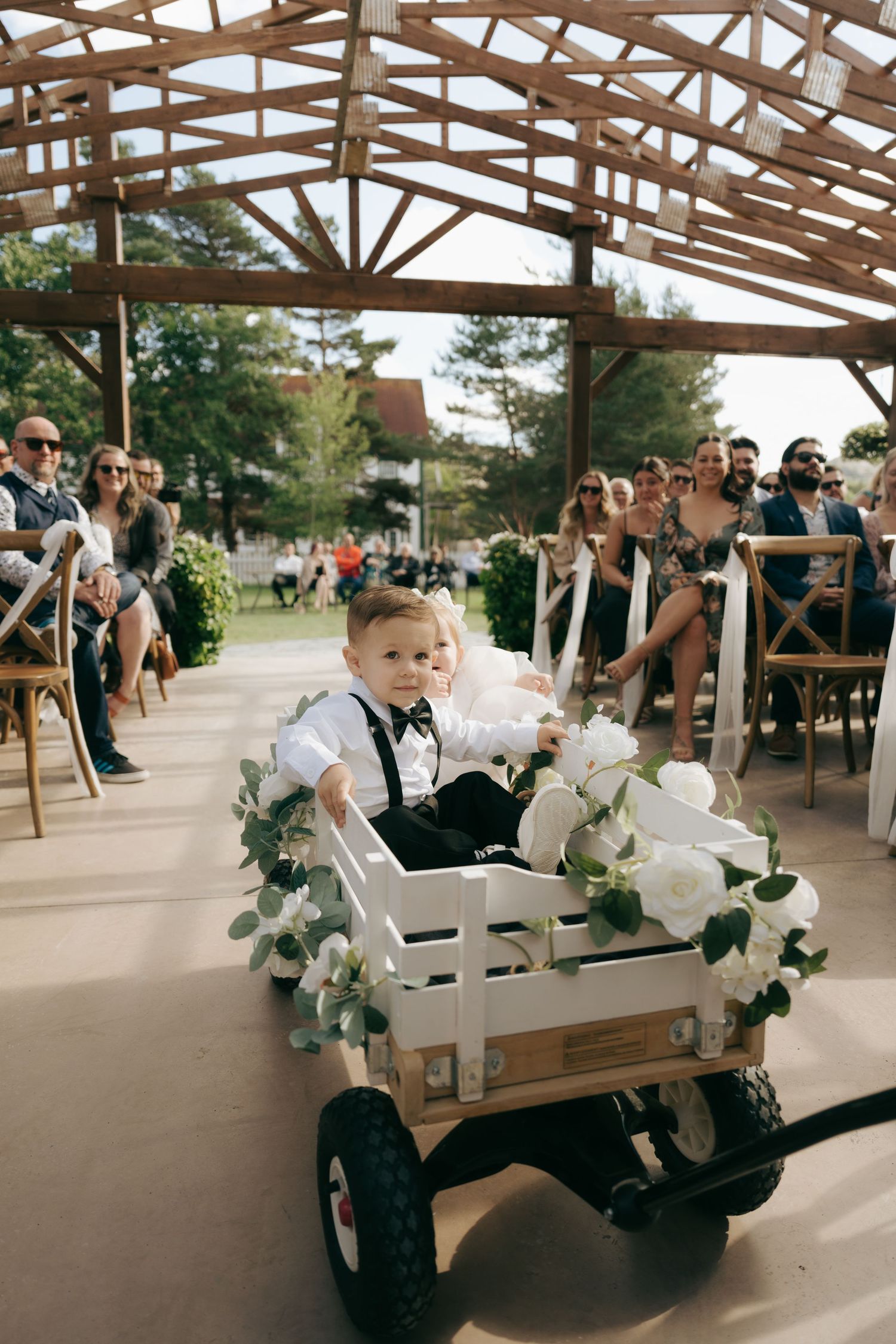A golf cart decorated with floral garlands transports wedding guests across a covered outdoor venue.