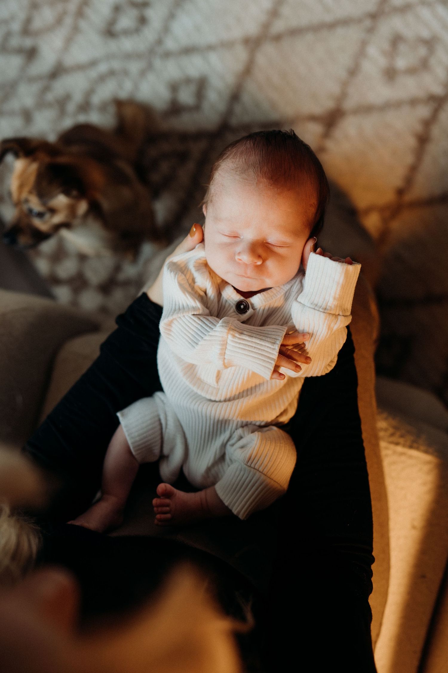 Baby wearing white sweater photographed from above on dark background.