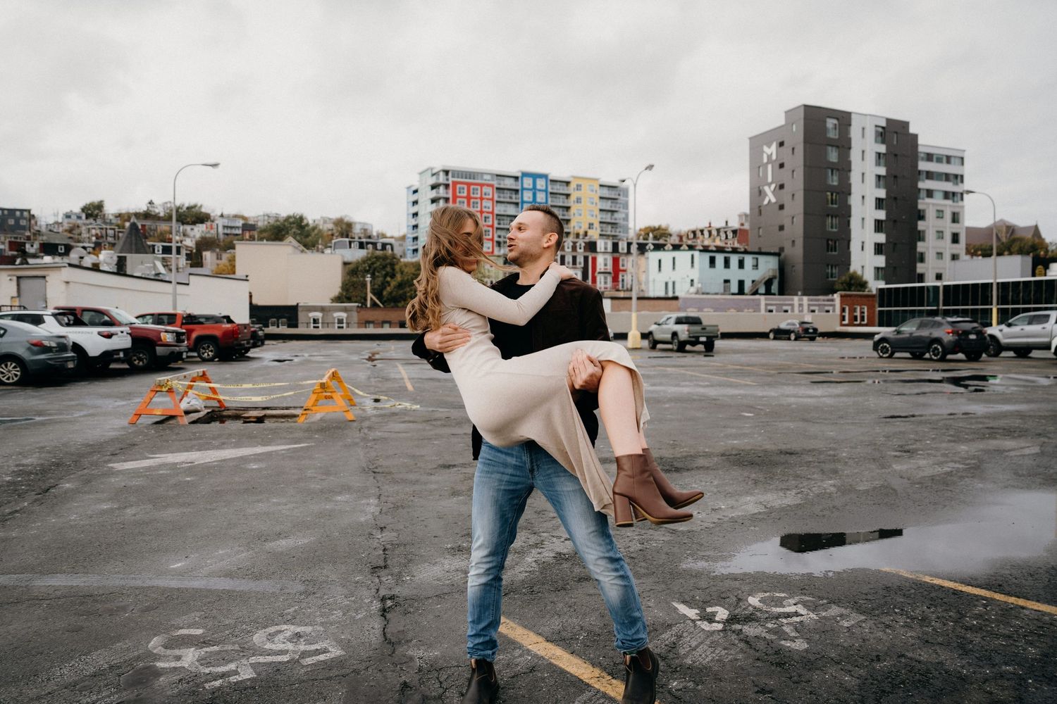 Artistic dance performance photographed in a stark urban environment with parked cars visible.