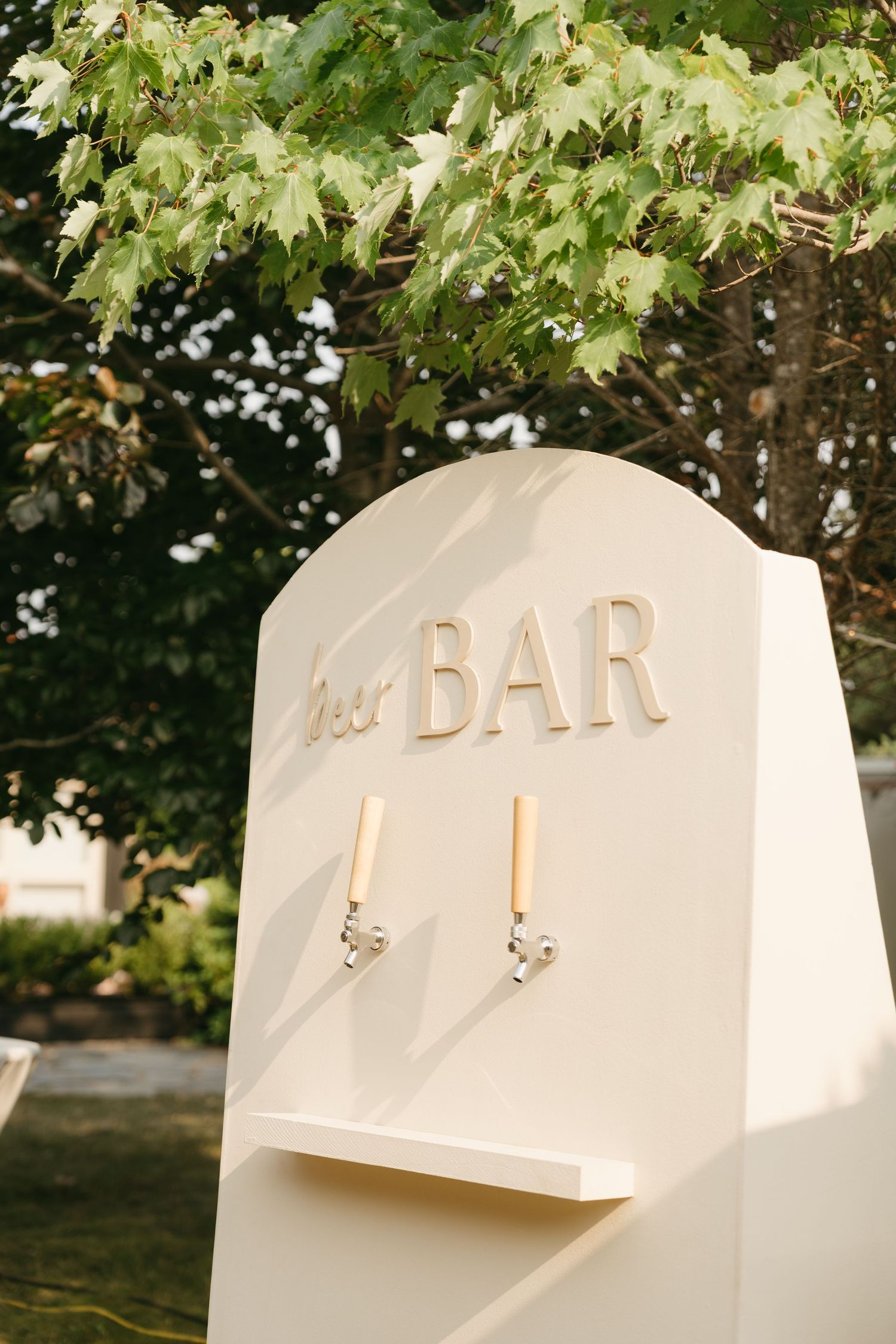 White modern bar sign installation among green tree foliage.