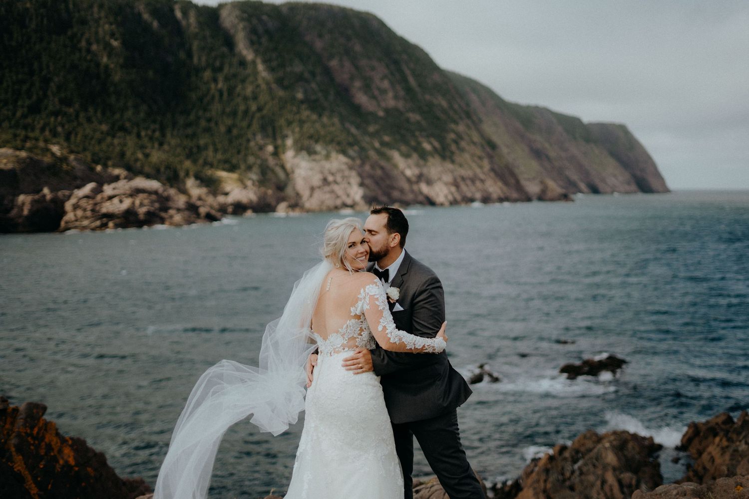 A couple embracing on coastal cliffs with dramatic ocean views.