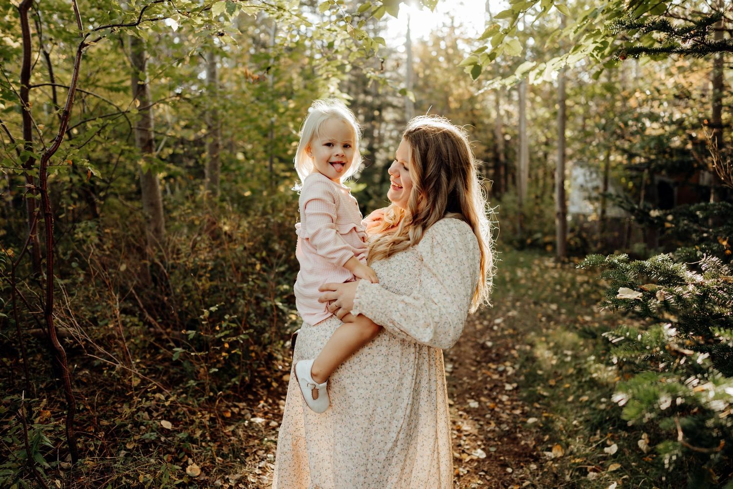 A loving family moment captured in autumn woods with warm golden sunlight filtering through the trees.