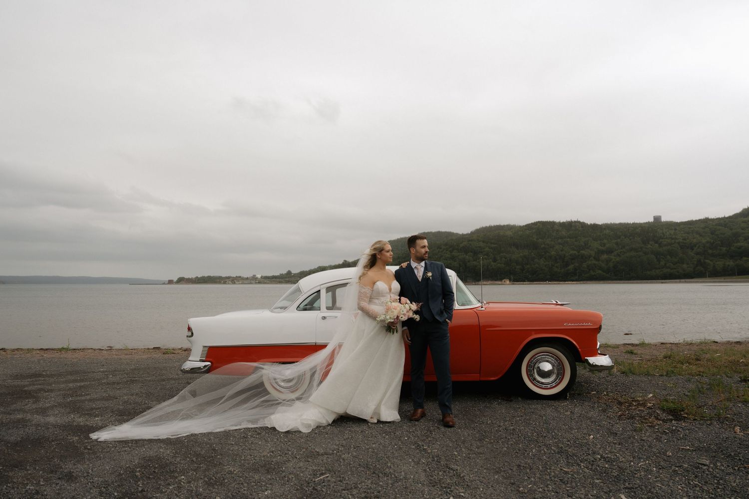 A romantic wedding photoshoot featuring a vintage orange car against scenic coastal landscapes.
