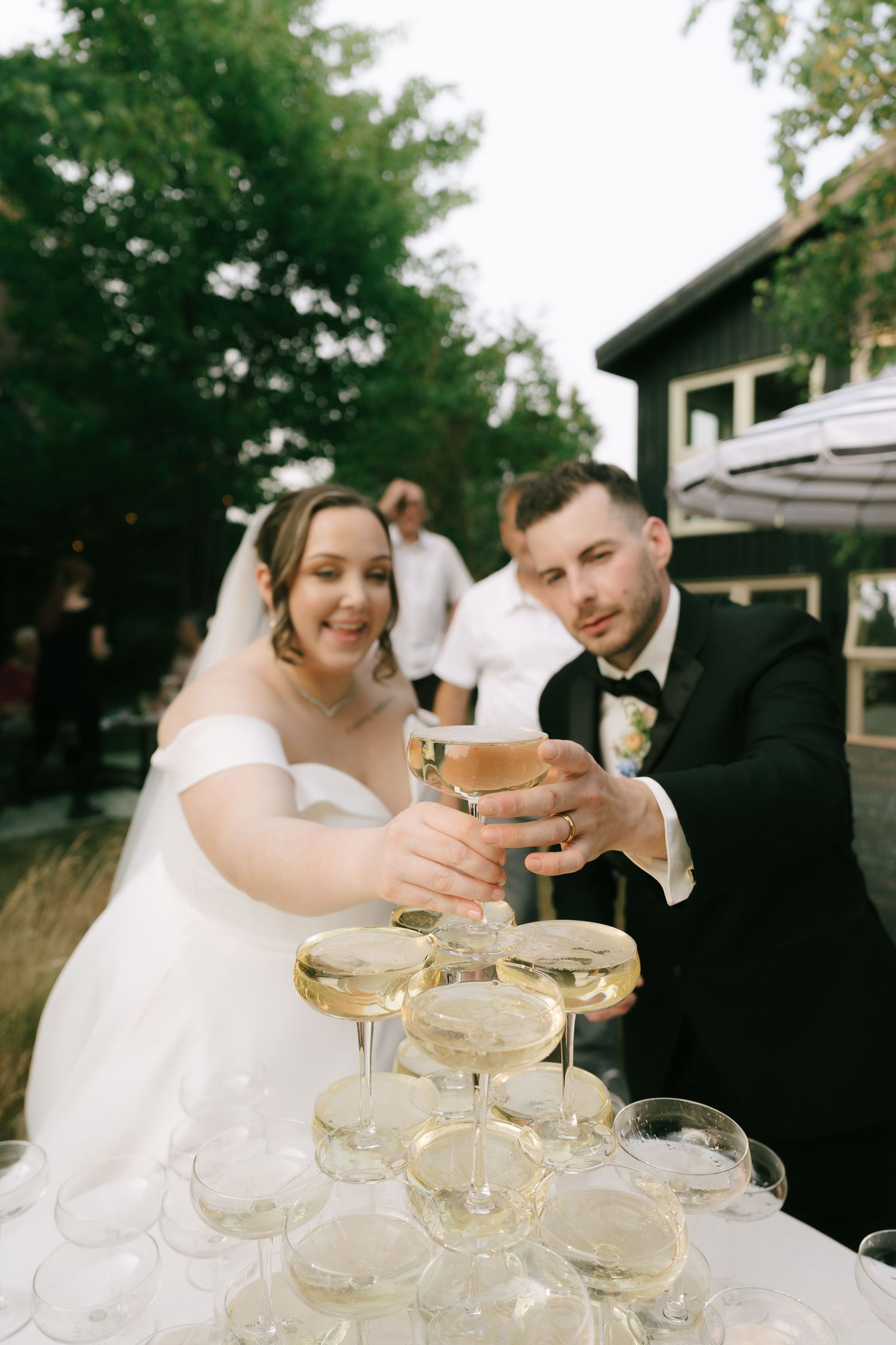 Celebratory moment of filling a champagne tower at an outdoor reception.
