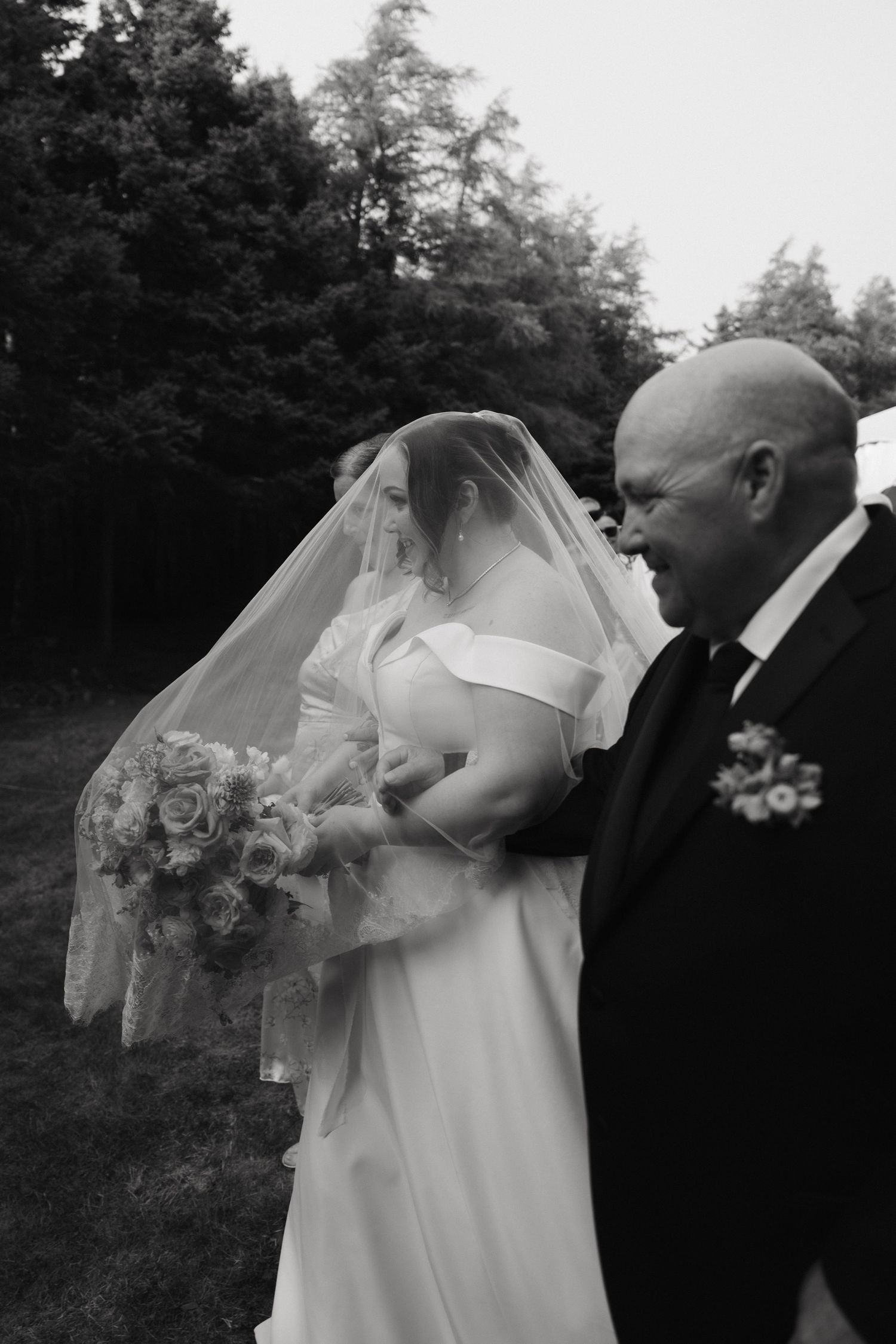 Black and white photo of tender moment between wedding couple during outdoor ceremony.