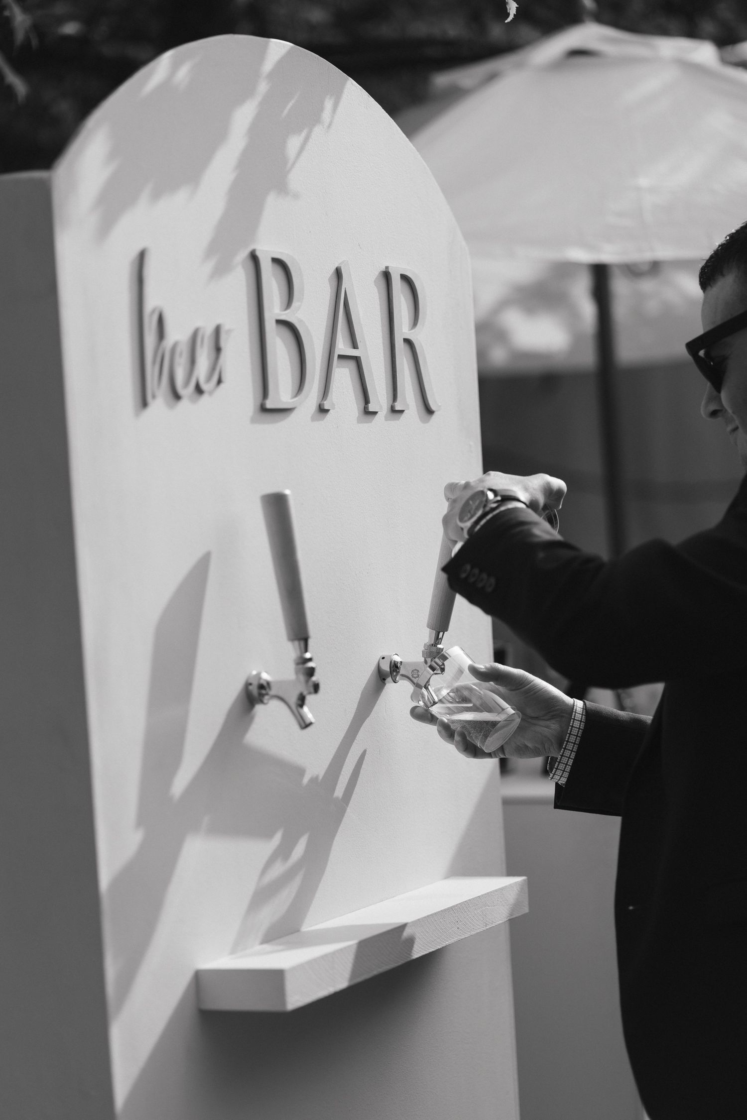White geometric bar signage casting shadows in outdoor event setting.