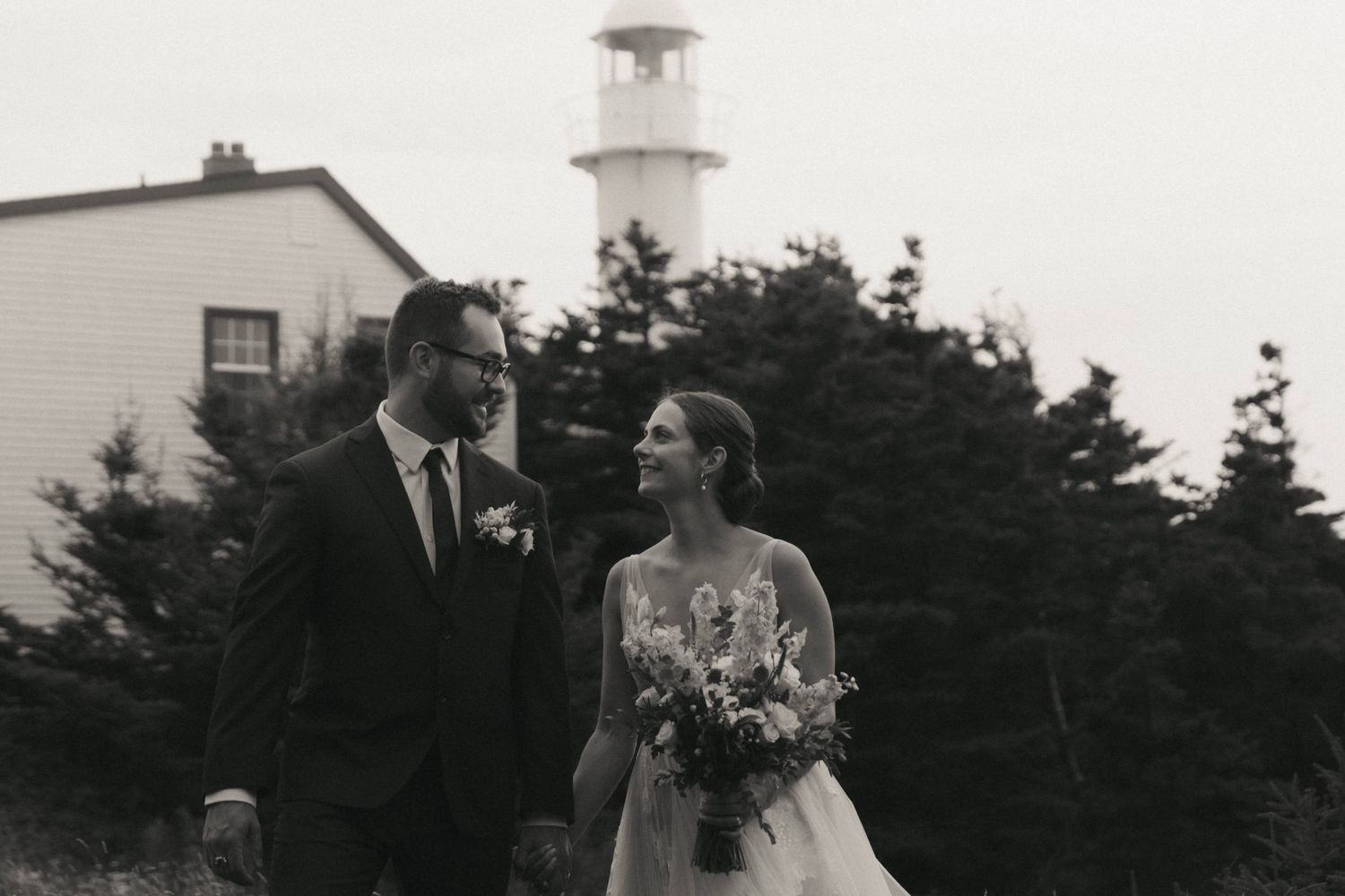Classic black and white lighthouse wedding photos showing intimate moments between couples backdropped by New England scenery.
