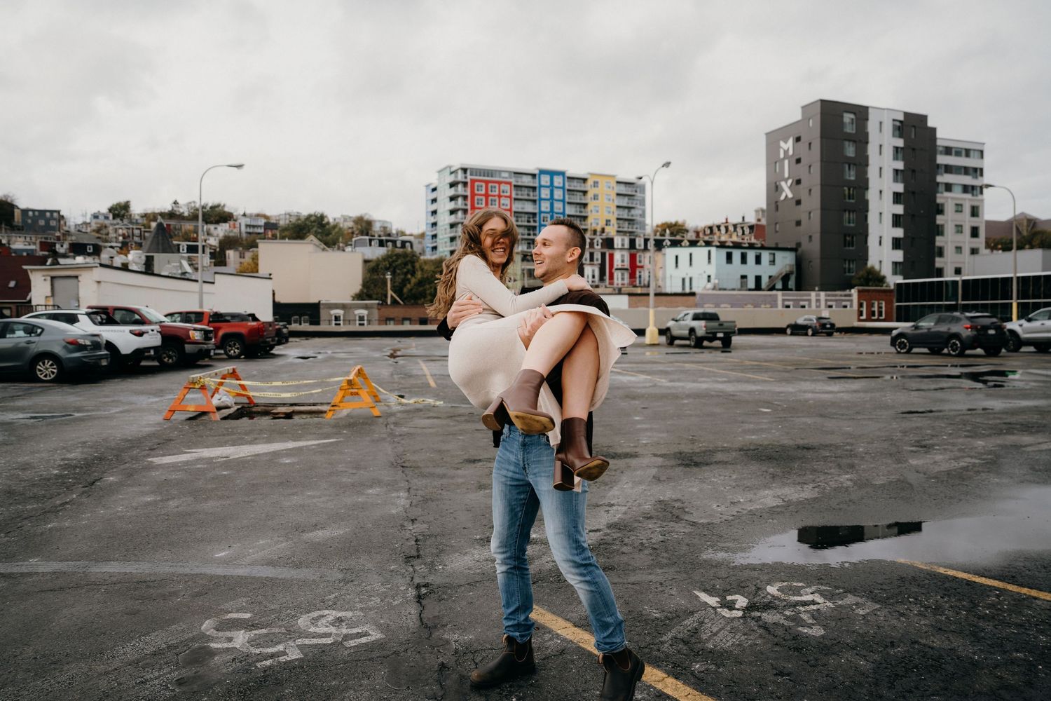 Graceful dance movement captured in an urban parking area with apartment buildings behind.
