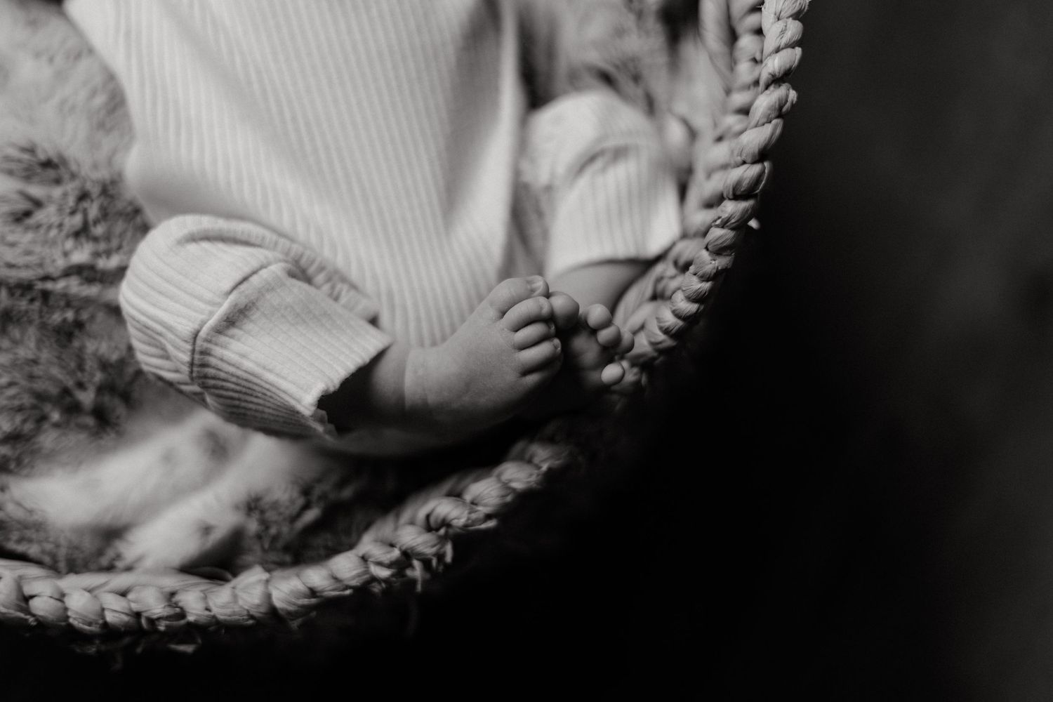 Black and white portrait of a baby sleeping peacefully in a woven basket.