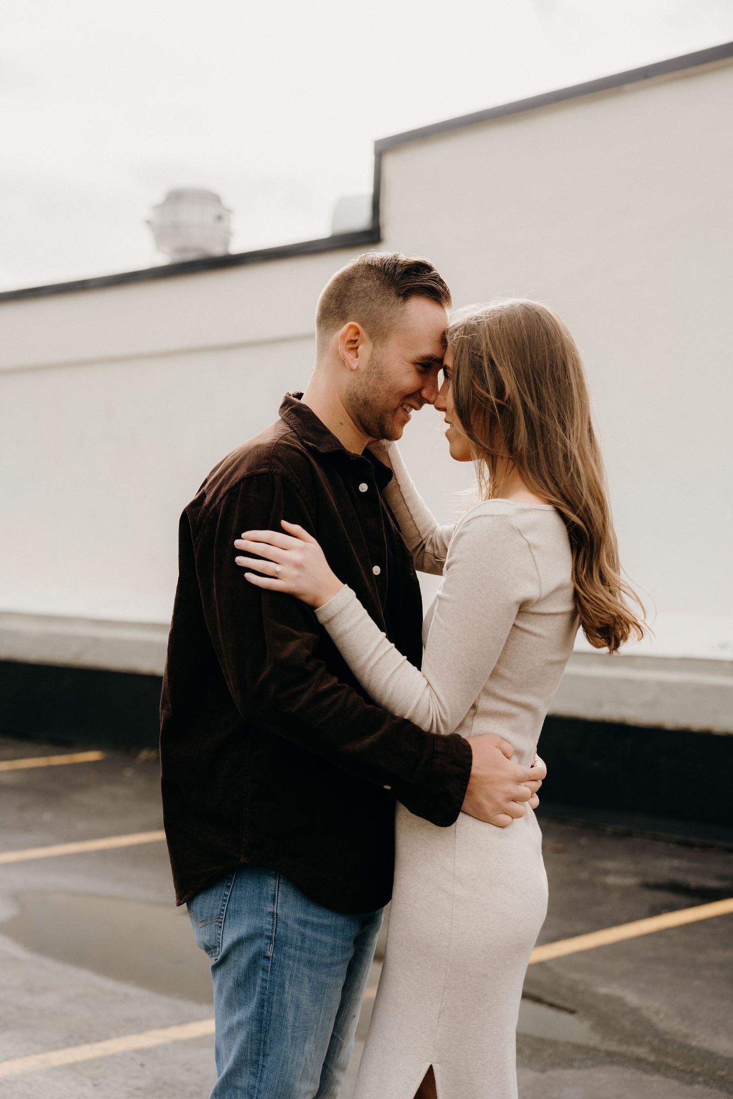 Romantic couple embracing in an urban parking lot setting.