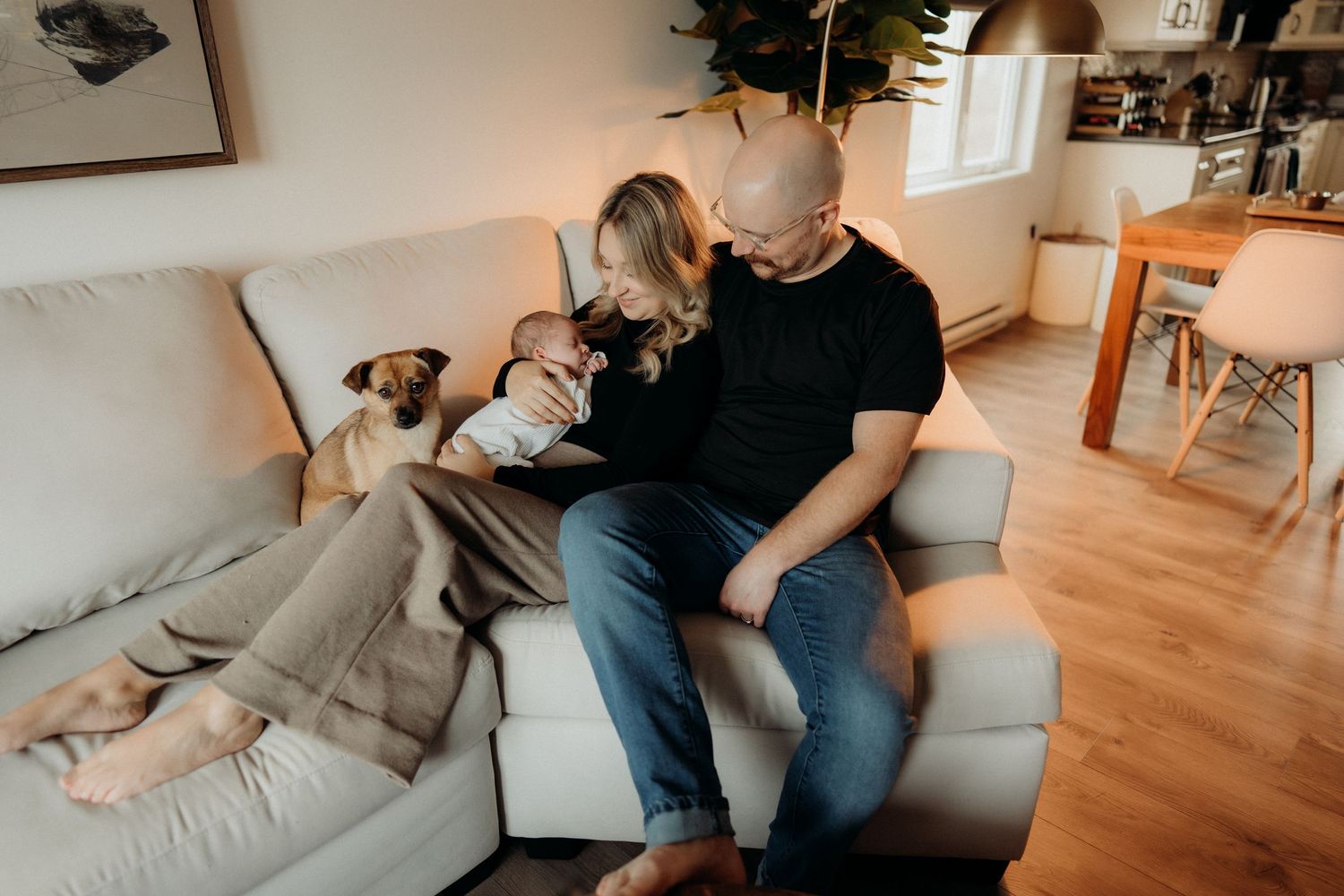 Family lounging together on a light gray couch in a modern living room setting.