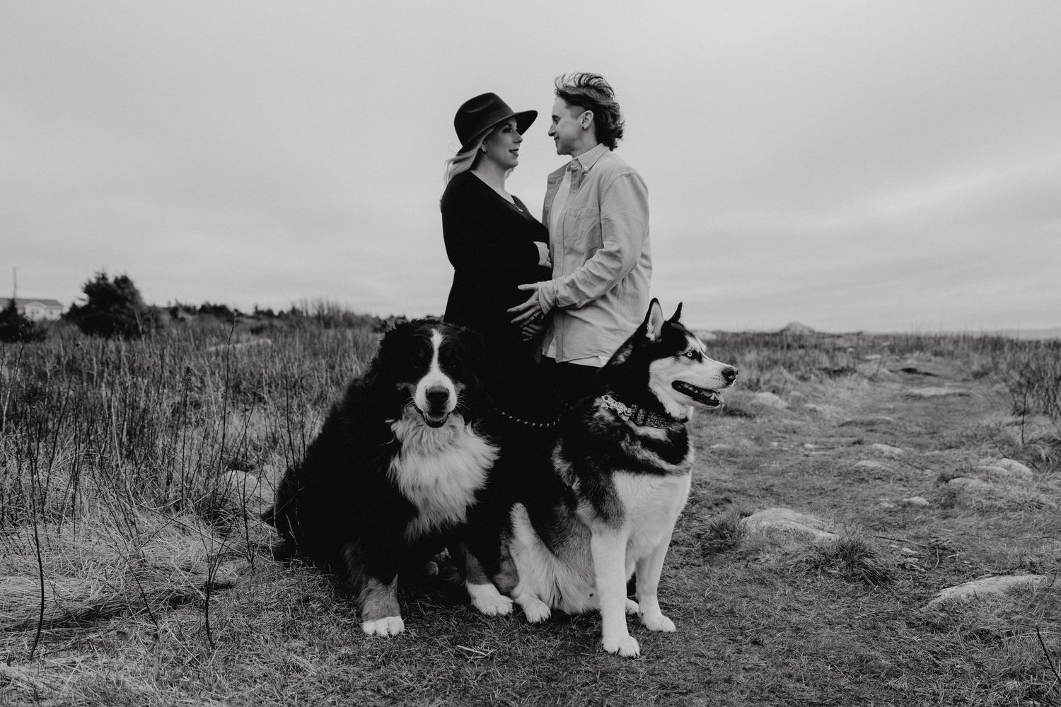 Family with dog poses together in black and white outdoor portrait series.