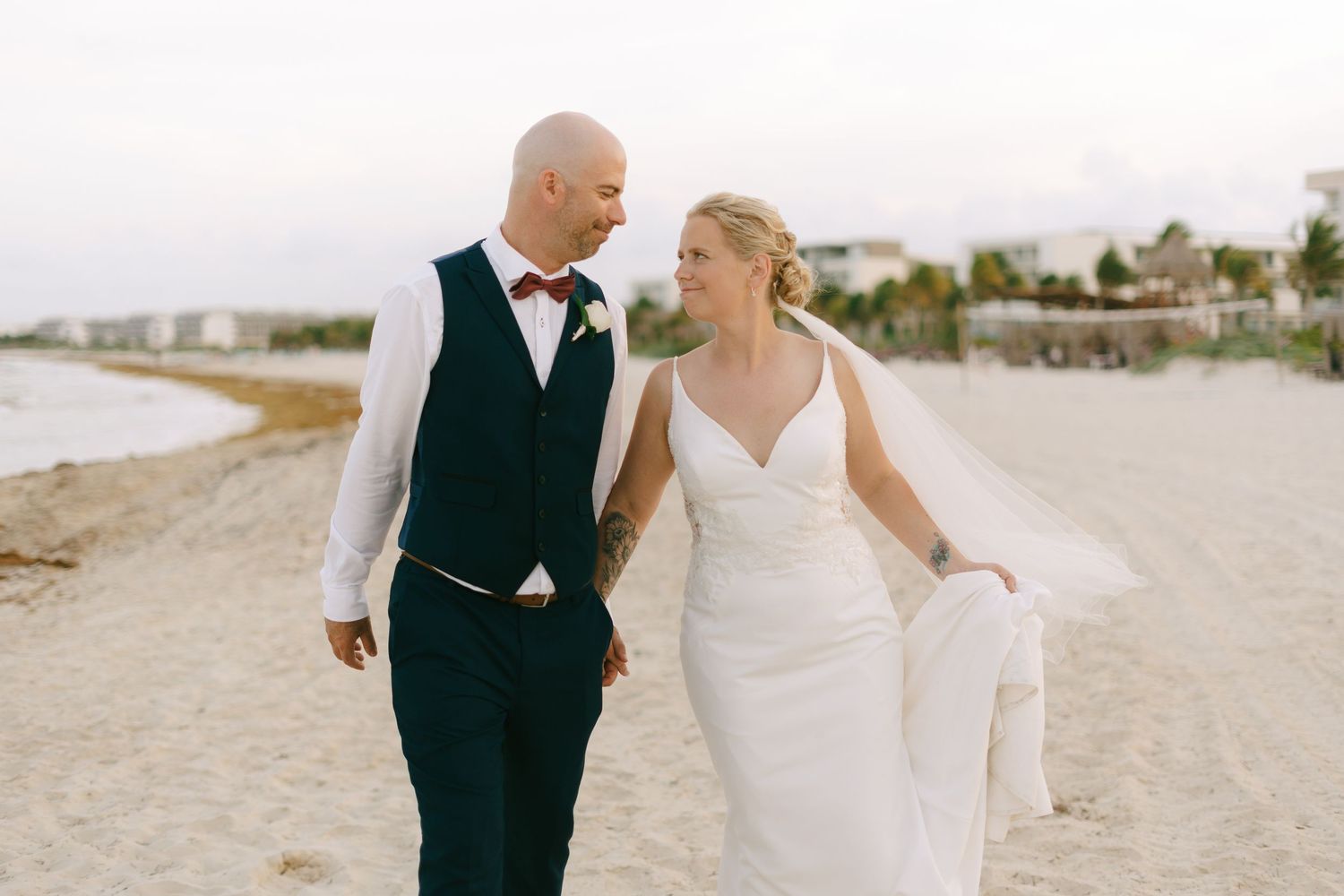 Couple embracing on a tropical beach with palm trees in the background.