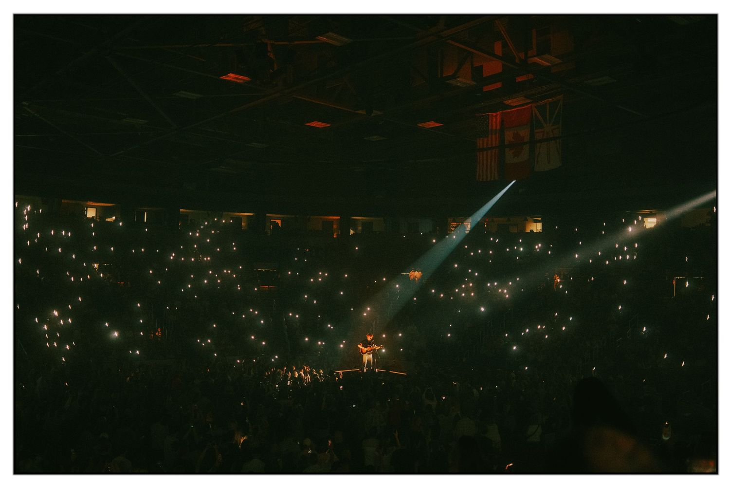 Aerial view of a dark cityscape at night with glowing orange lights scattered across the urban landscape.