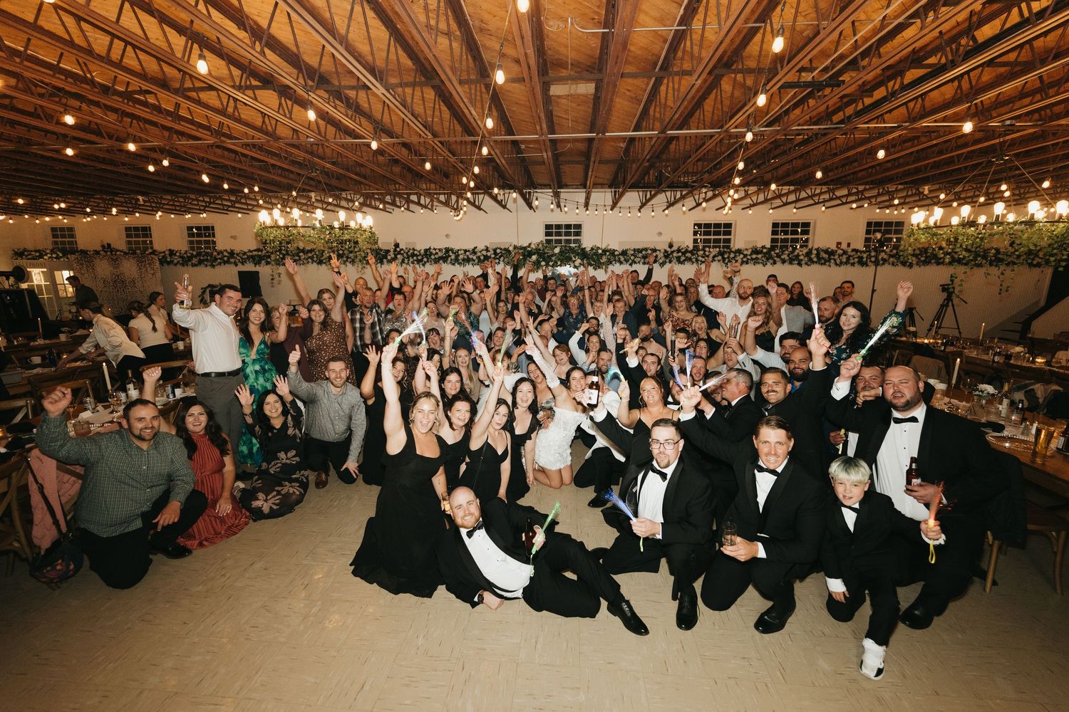 A large group of people seated in rows at a formal indoor event with string lights overhead.