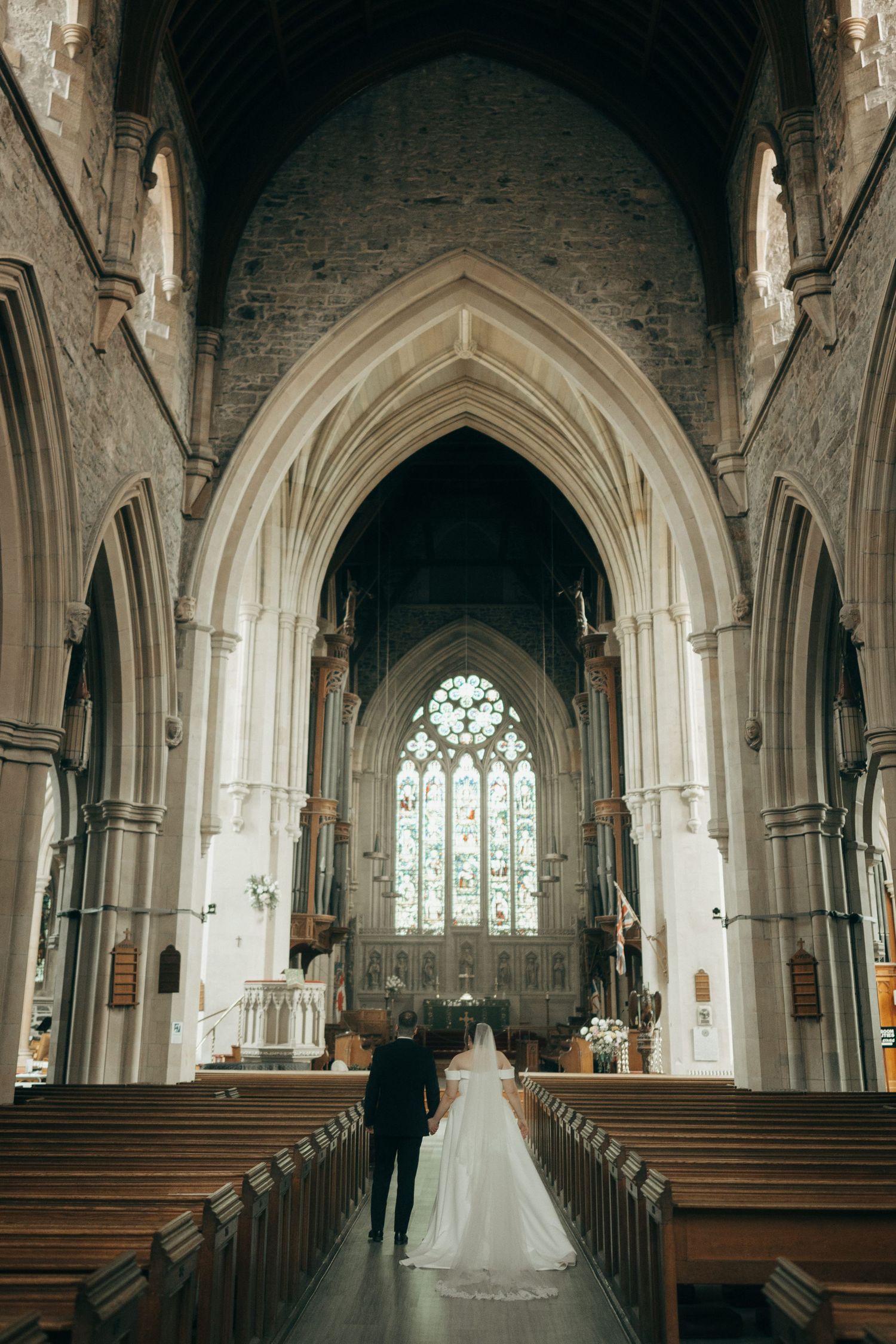 Wedding ceremony setting in a grand cathedral with arched stone architecture and rows of wooden pews.