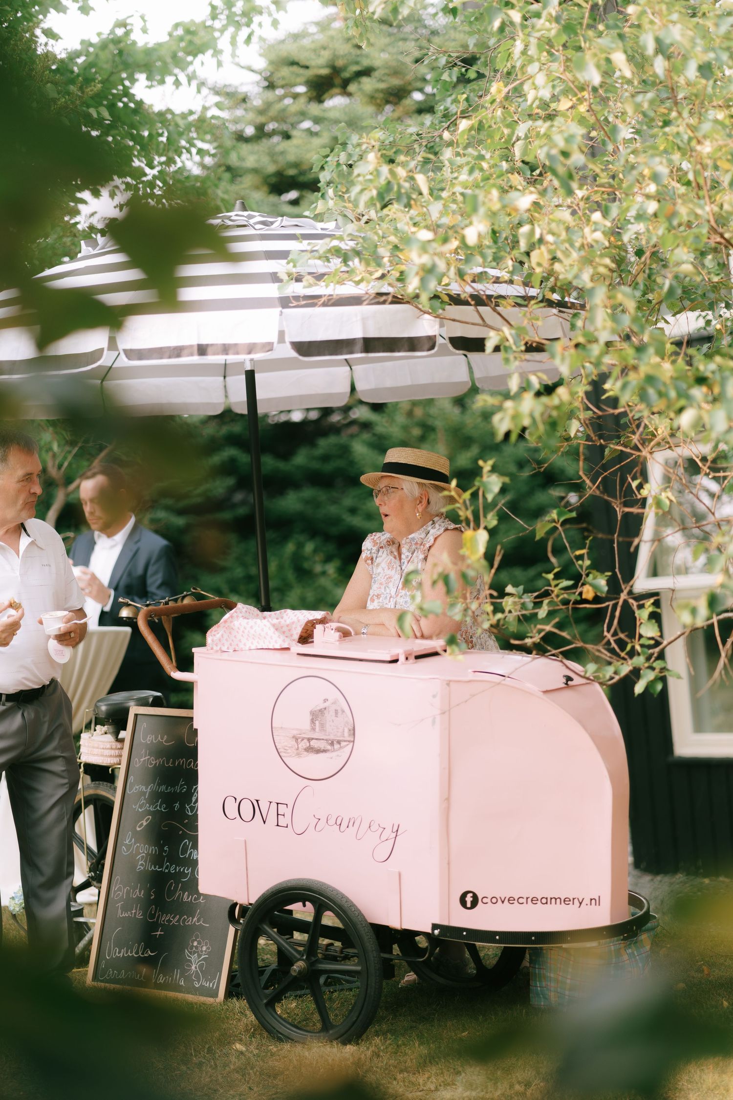 Pink retro-styled beverage cart set up outdoors under trees for event service.