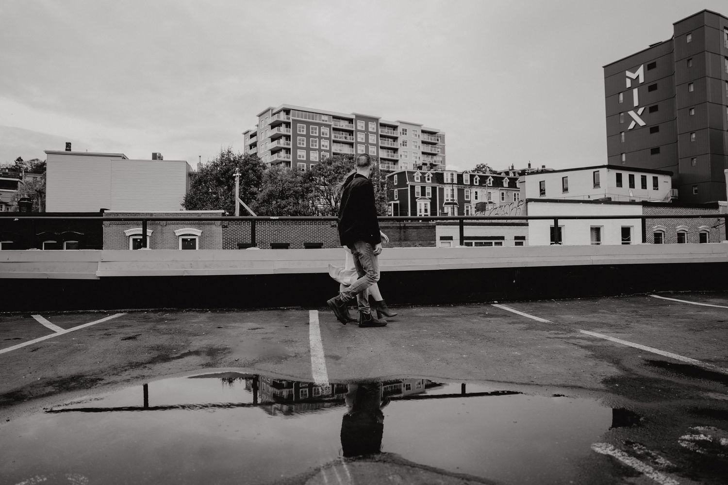 A monochromatic wide-angle view of an urban rooftop parking area.