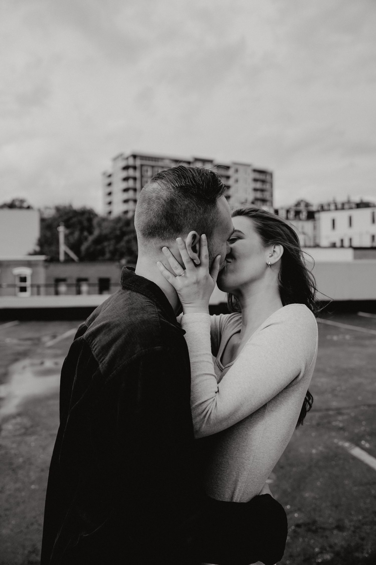 A close-up of a romantic moment between a couple with modern buildings in soft focus.