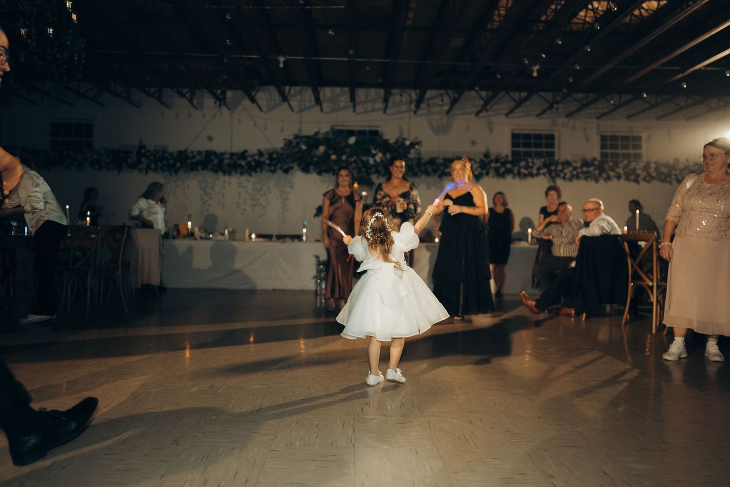 People dancing together at a wedding reception in a dimly lit venue with decorative lighting.
