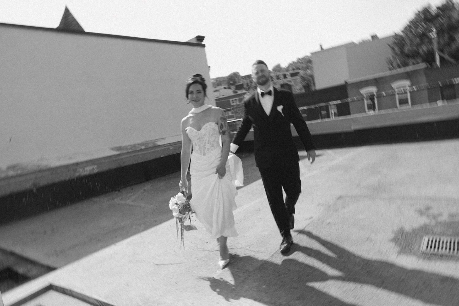 Black and white photo of a bride and groom walking together outdoors on their wedding day.